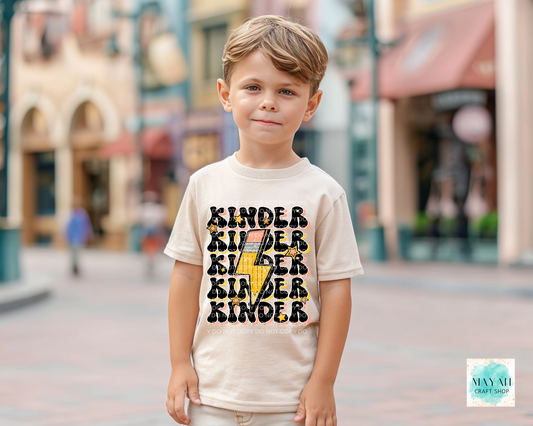 Child wearing a shirt with 'Kinder' text in an urban setting