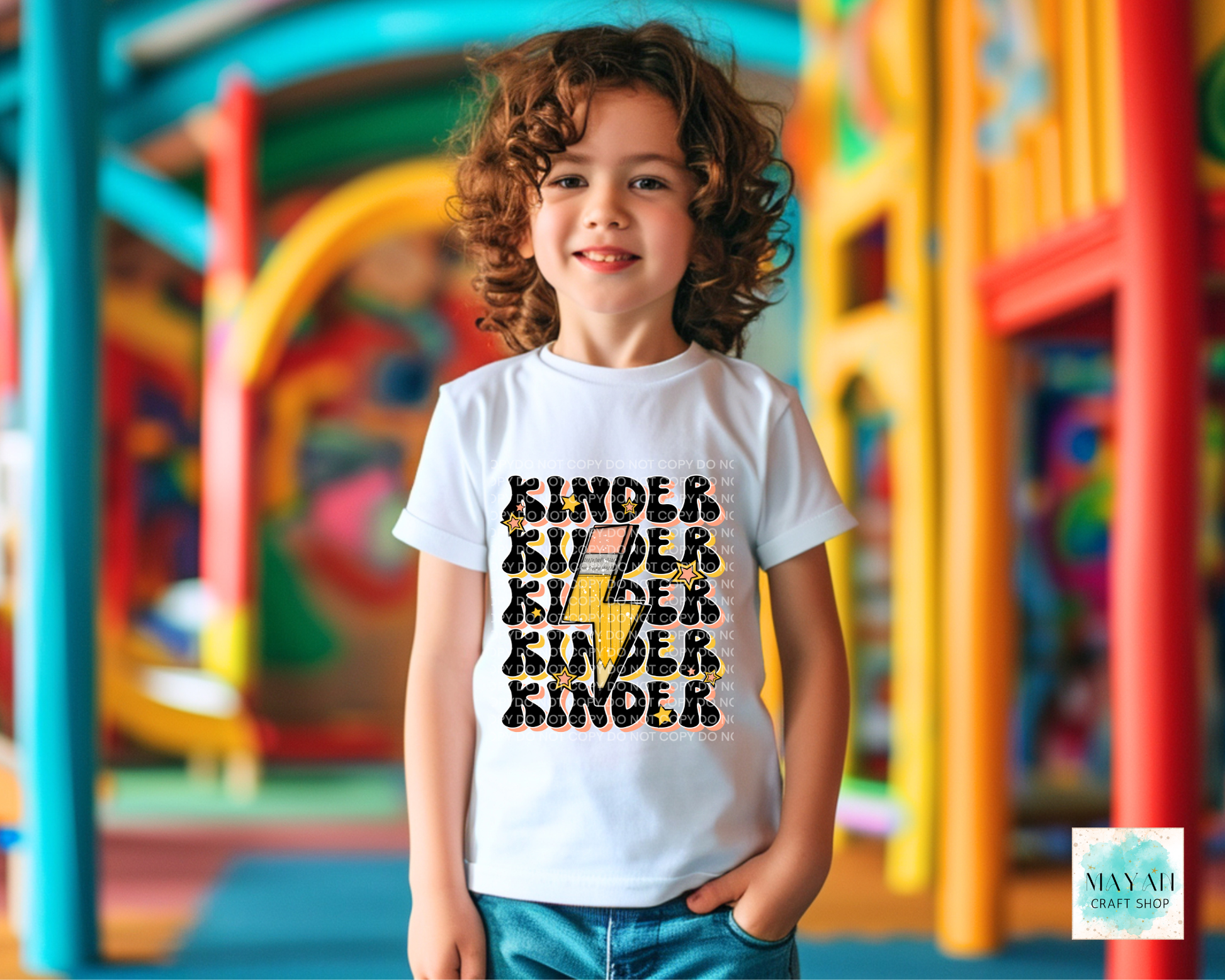 Child wearing a white t-shirt with 'Kinder' text design in a colorful playground setting