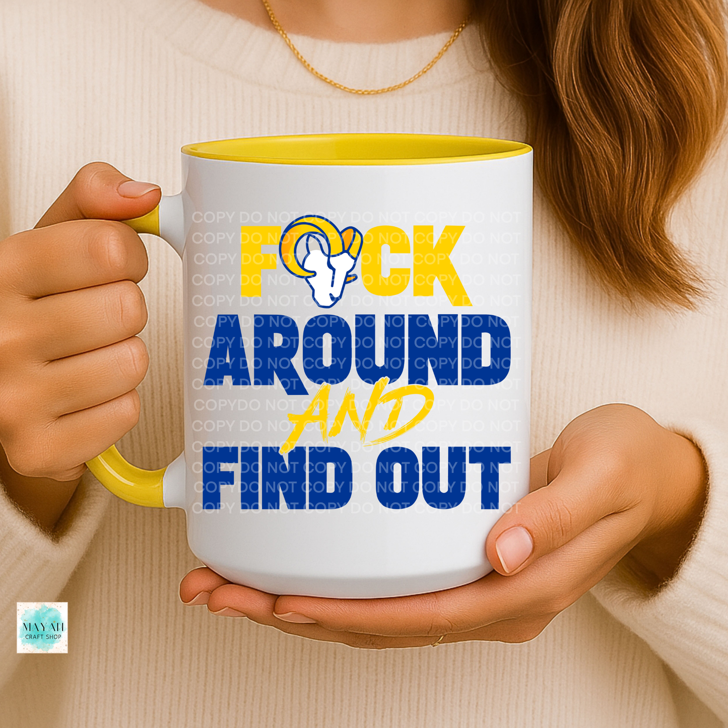 Person holding a mug with text and logo, wearing a beige sweater.