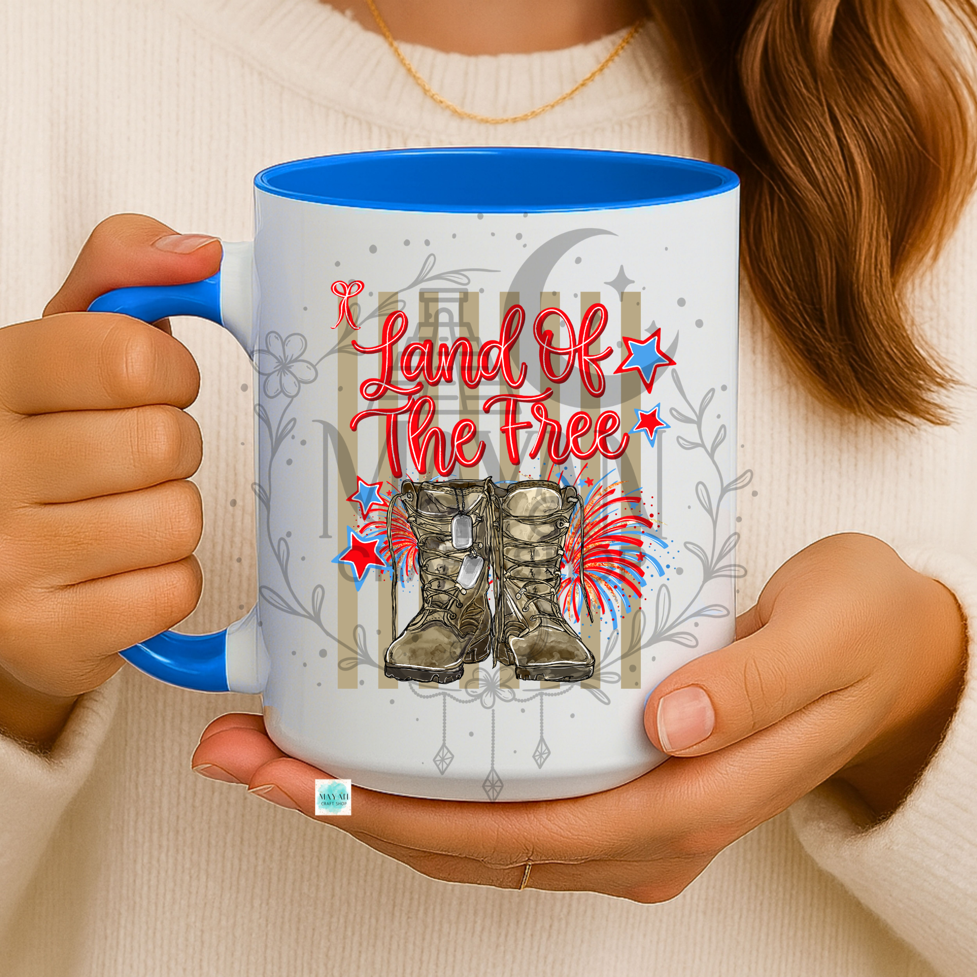 Person holding a mug with 'Land of the Free' design featuring boots and stars.