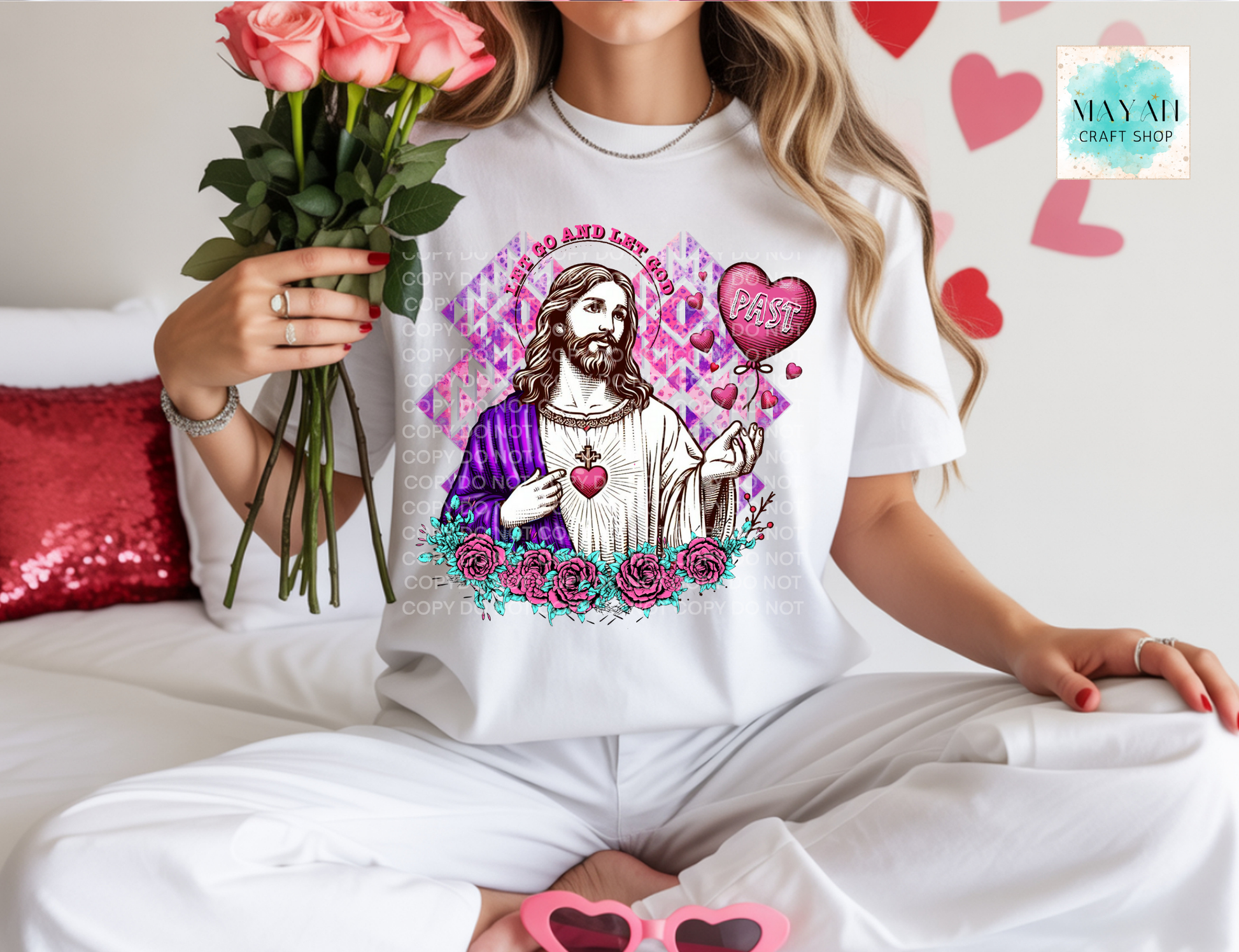 Person wearing a white t-shirt with a graphic design of Jesus holding flowers, surrounded by hearts and roses, holding pink sunglasses and flowers.