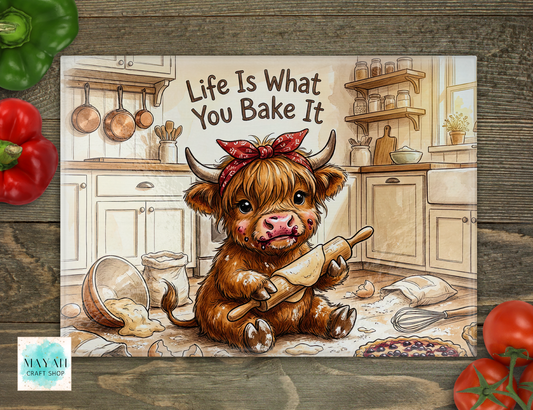 Cartoon cow in a kitchen holding a rolling pin with 'Life Is What You Bake It' text, surrounded by vegetables on a wooden surface.