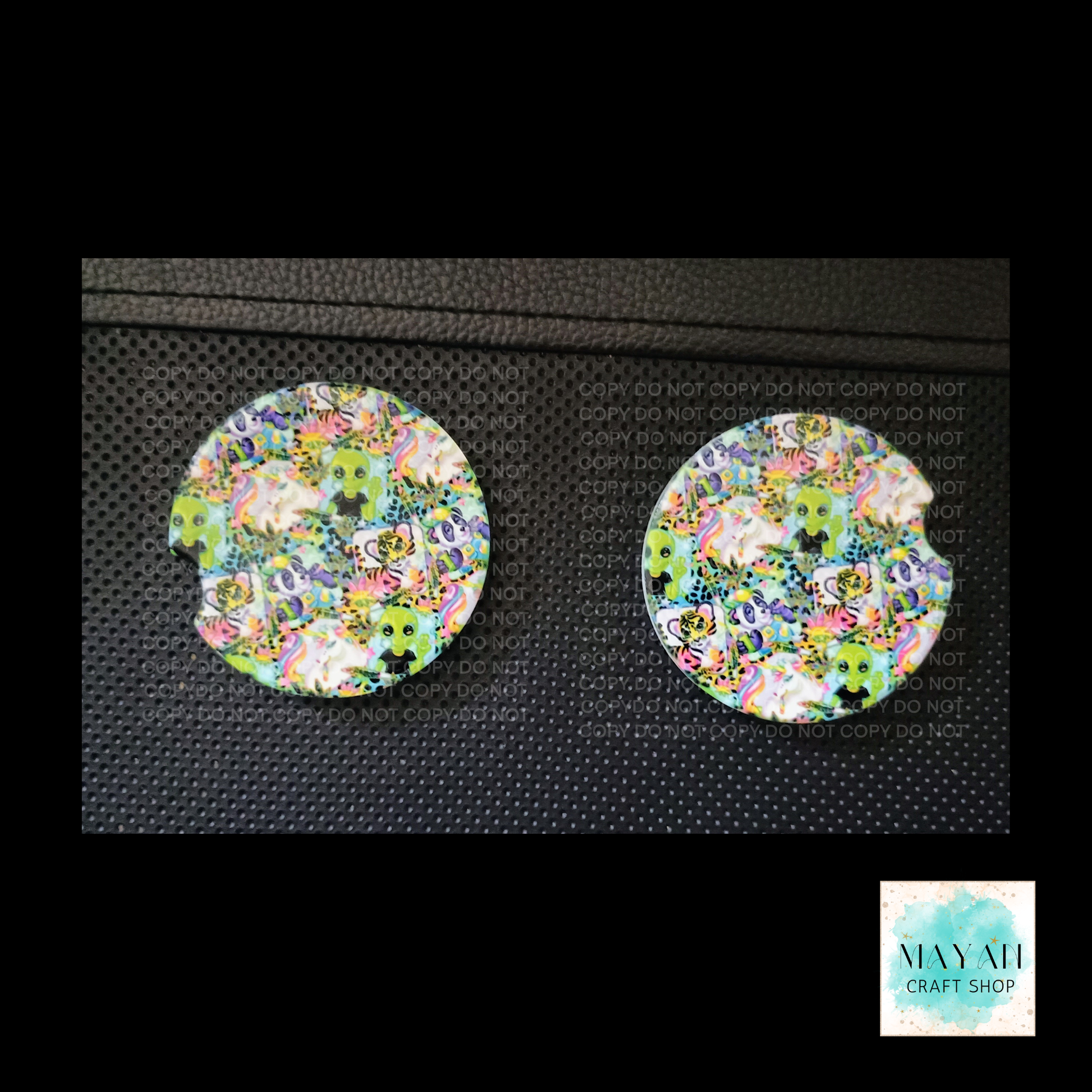 Pair of round, multicolored car coasters on a textured black surface.