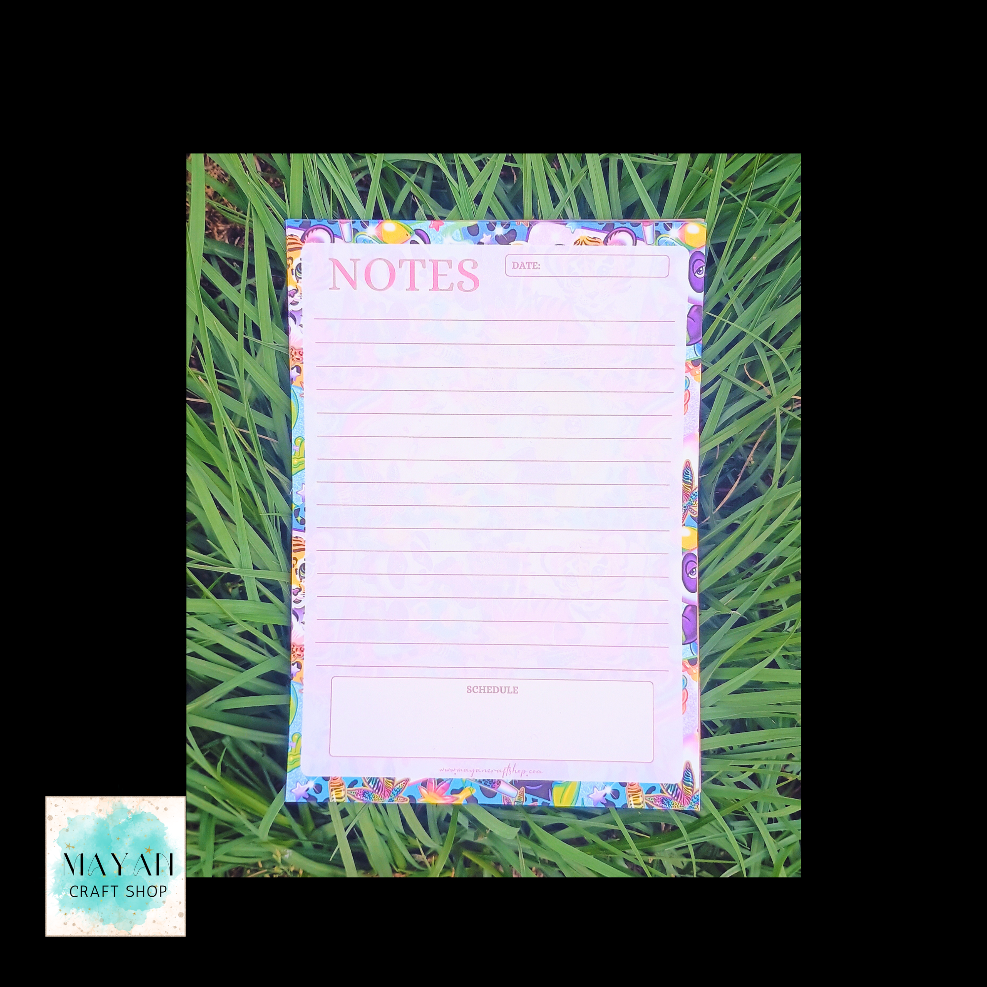 Notepad with colorful border on grass.