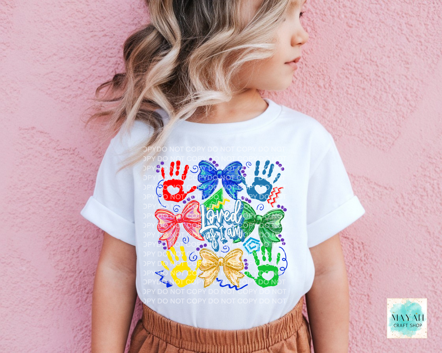 Child wearing a white t-shirt with colorful handprints and bows design against a pink background