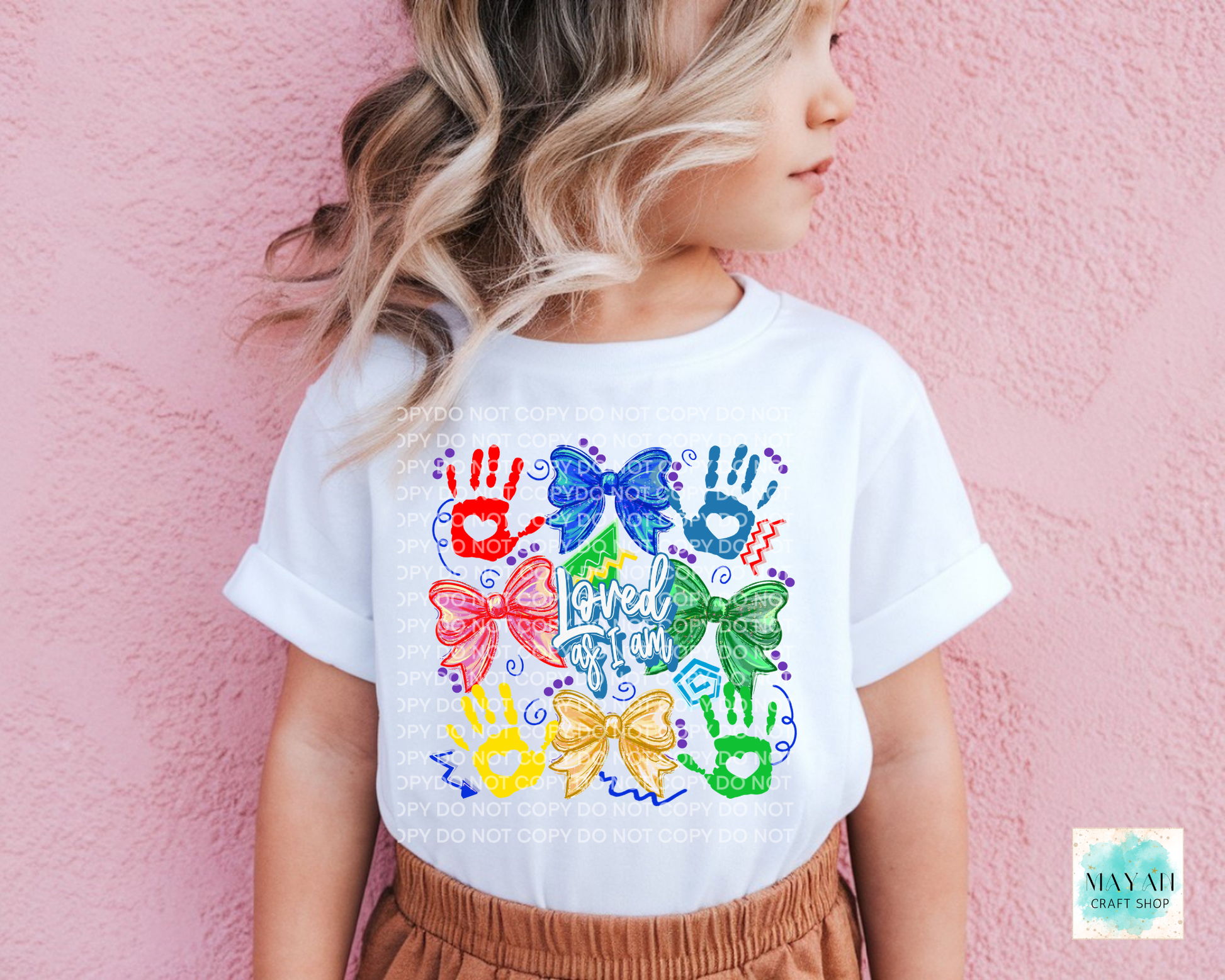 Child wearing a white t-shirt with colorful handprints and bows design against a pink background