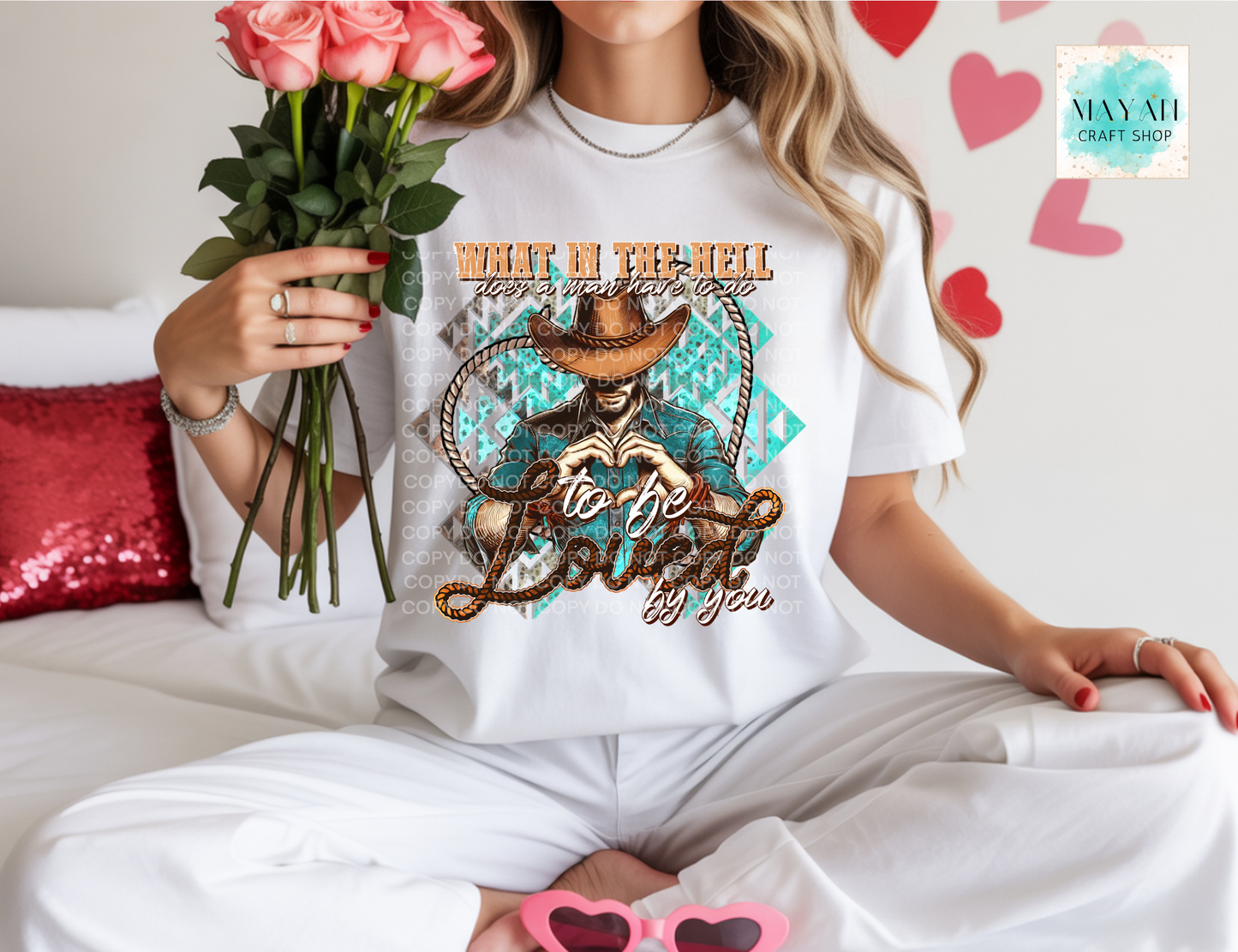 Person wearing a white t-shirt with a graphic design and text, holding flowers and sunglasses.