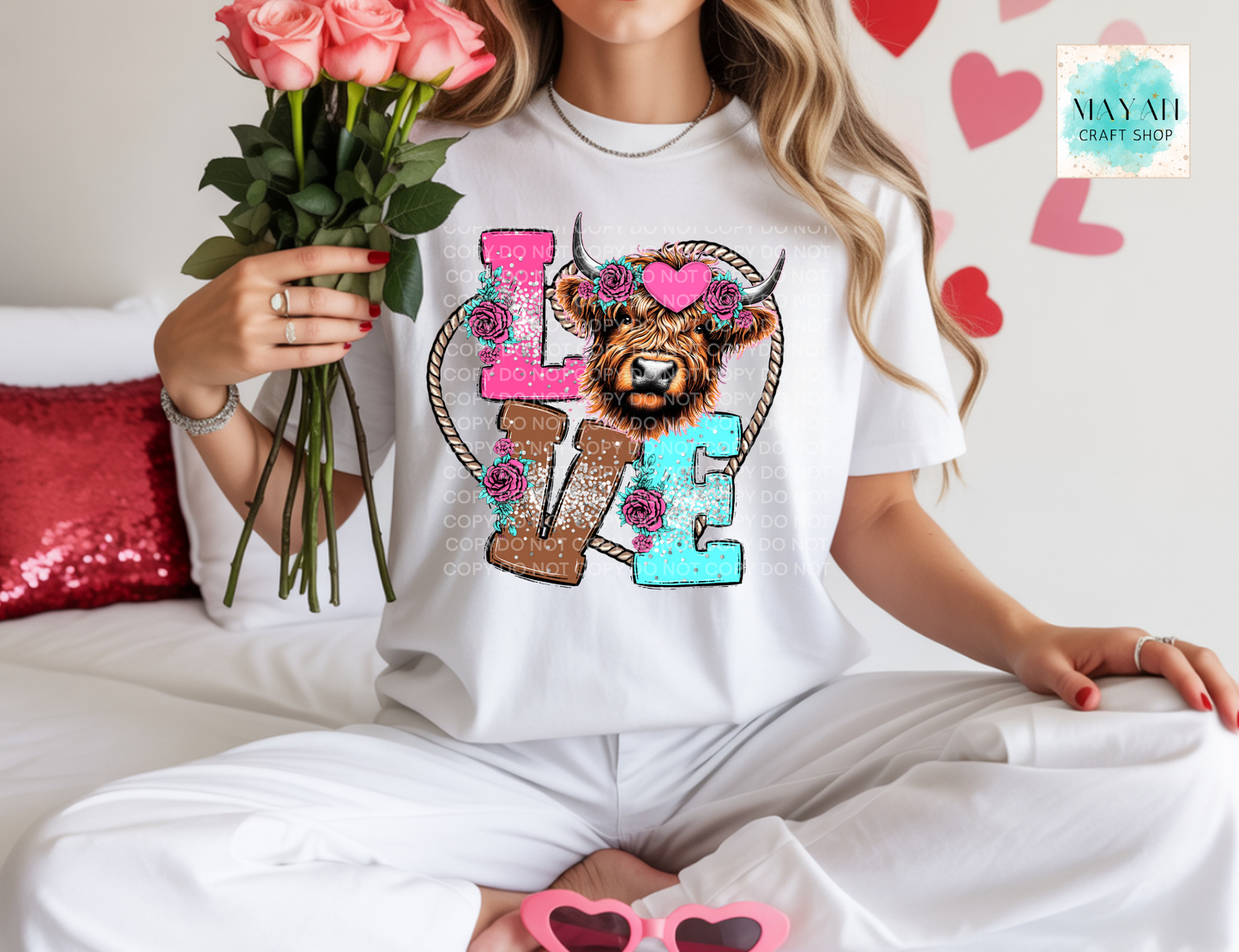 Person wearing a white t-shirt with a colorful design holding flowers and sunglasses.