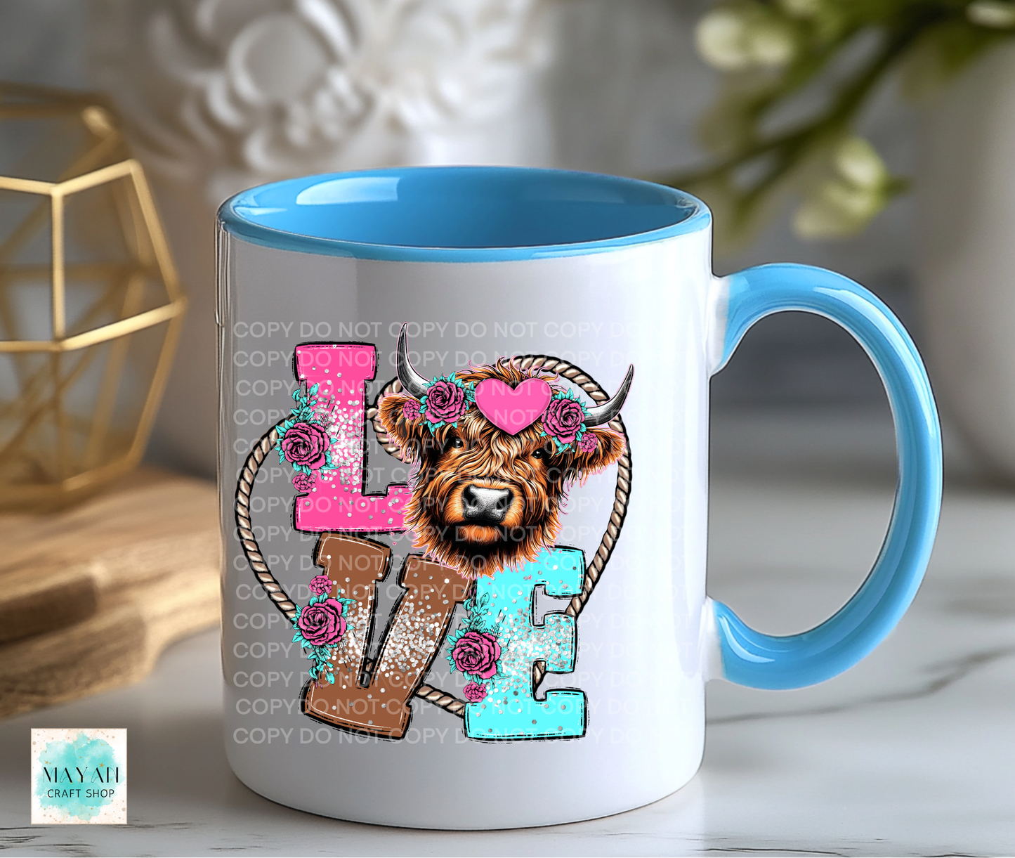 Mug with a decorative design featuring a cow and colorful letters on a white surface.
