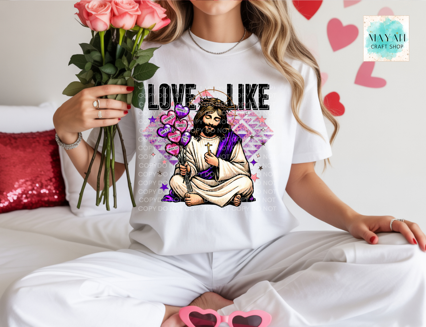 Person wearing a white t-shirt with a graphic design of Jesus and hearts, holding flowers.
