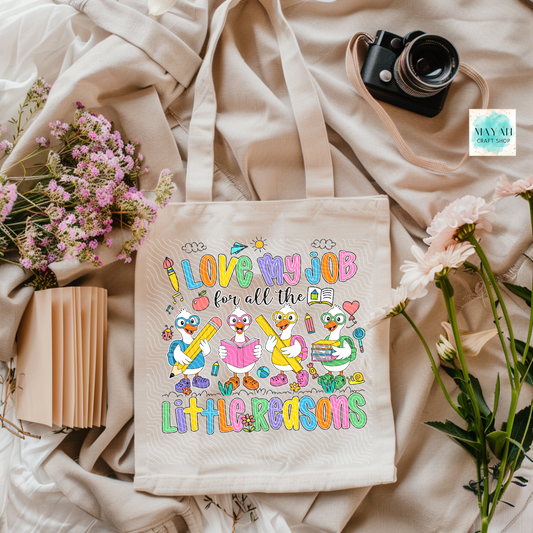 Tote bag with colorful design and text on a soft fabric background with flowers and a camera.