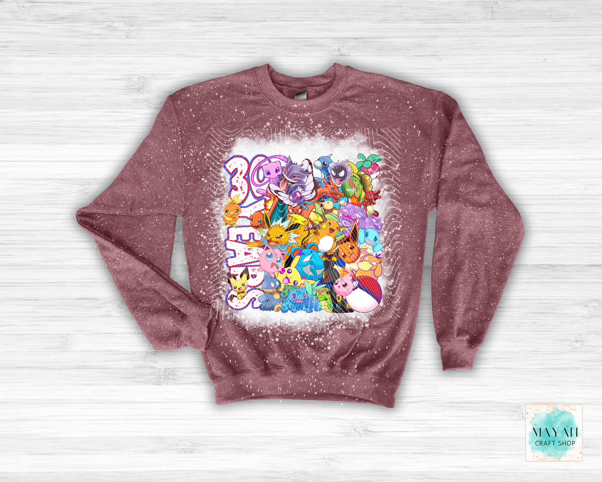 Maroon sweatshirt with colorful graphic design on a white wooden background