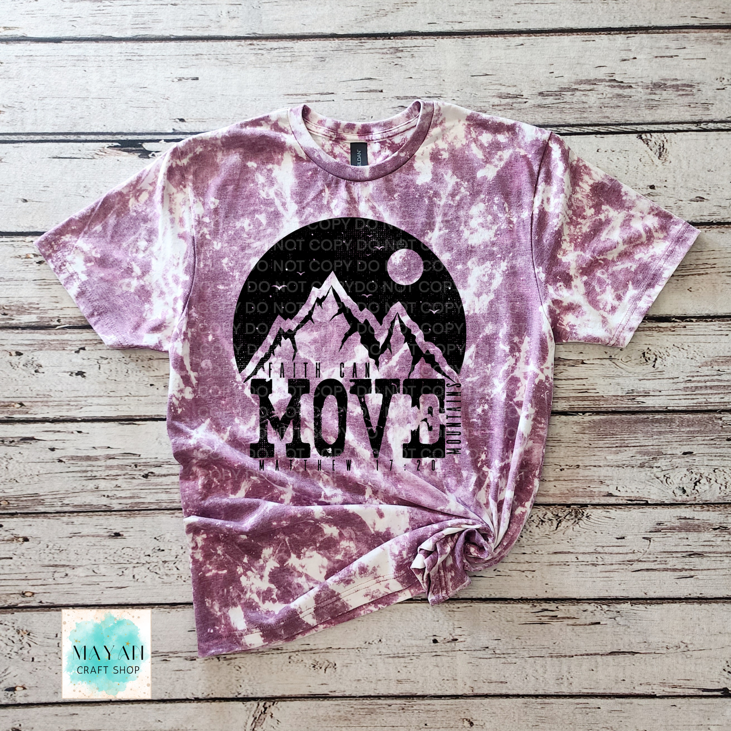 Tie-dye t-shirt with mountain graphic and 'Move Mountains' text on a wooden surface