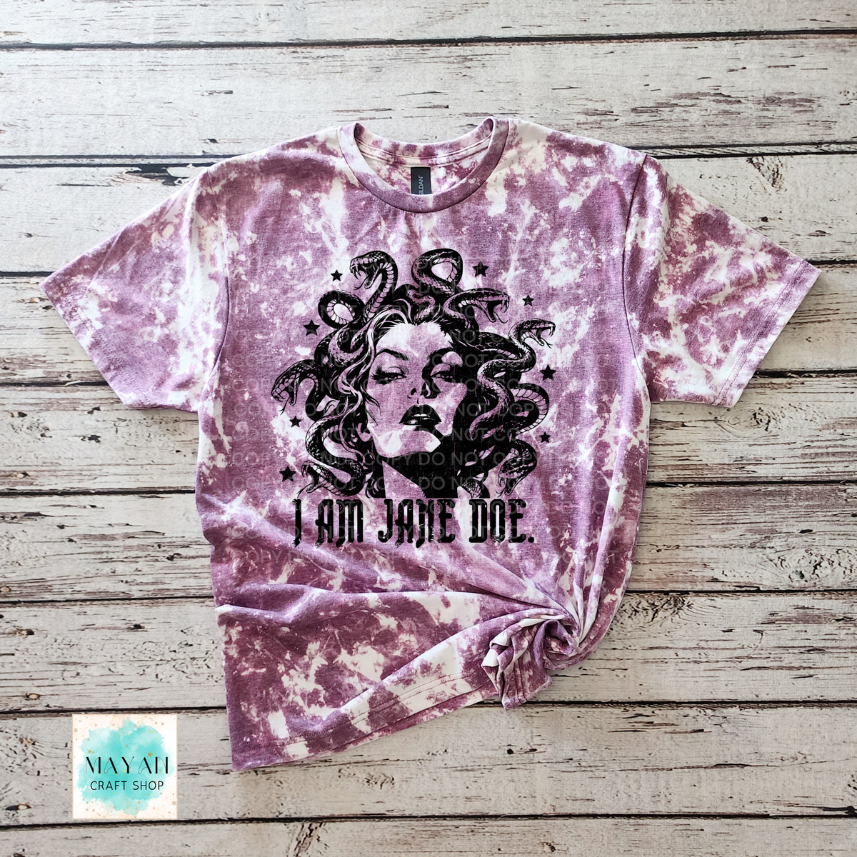 A heather maroon bleached t-shirt featuring a black graphic of Medusa's face with snakes for hair and the text 'I AM JANE DOE.' printed below it.