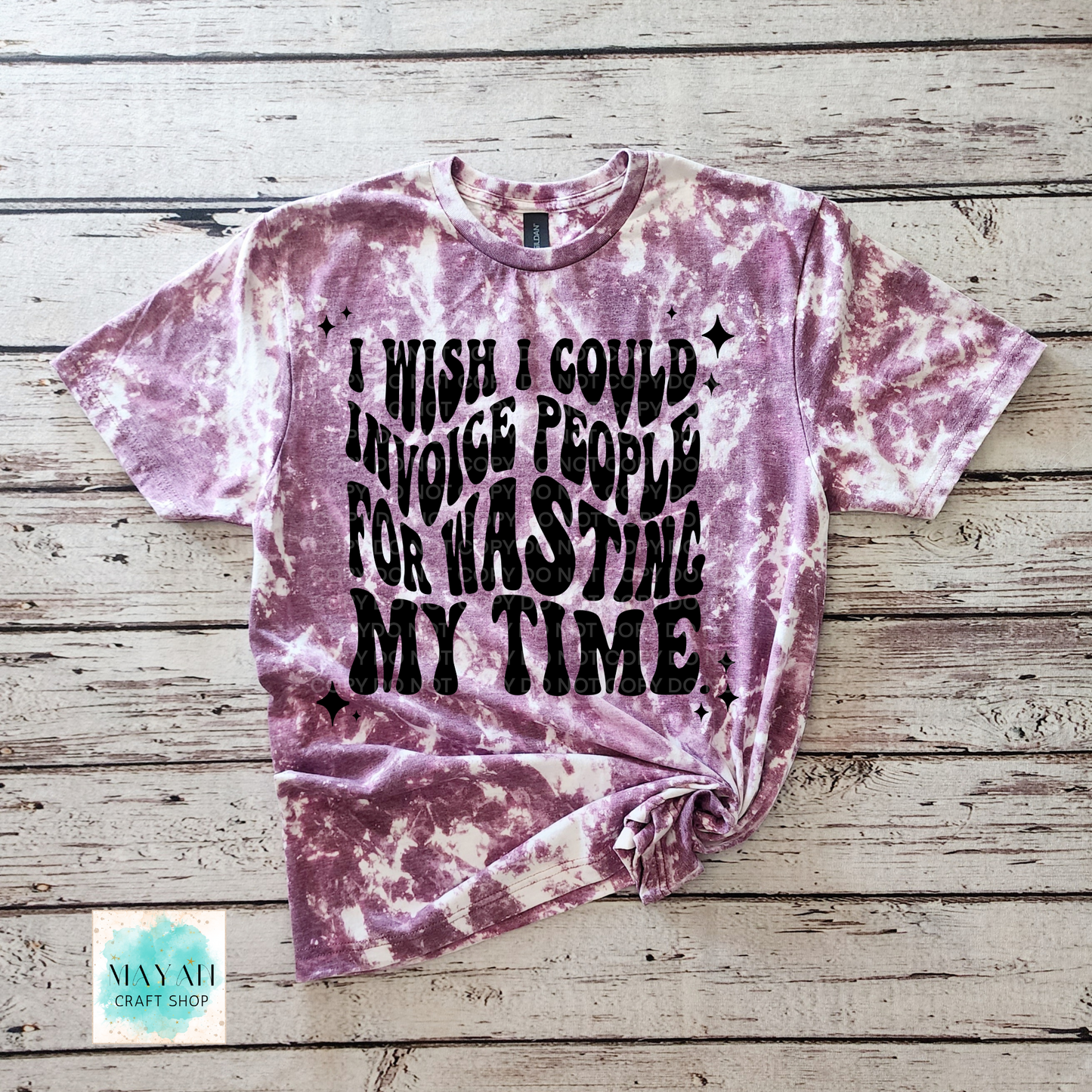 Tie-dye t-shirt with text on a wooden surface, featuring the brand 'Mayan Craft Shop'.