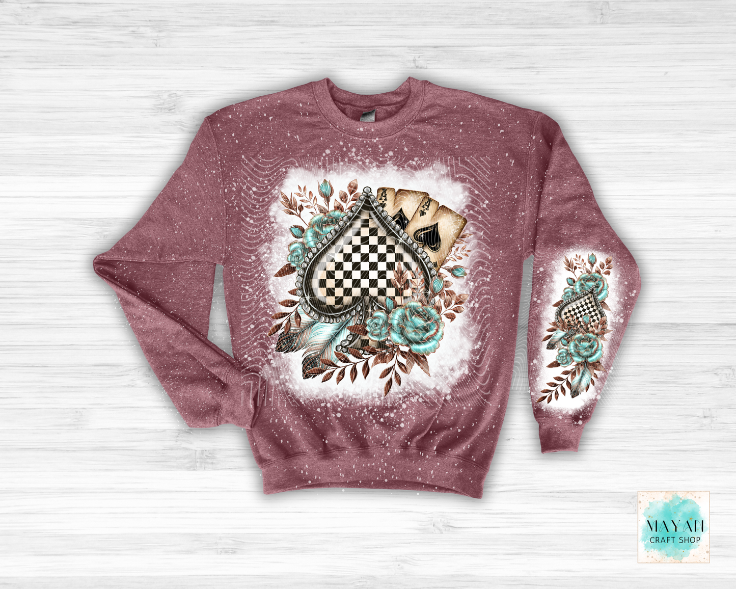 Maroon sweatshirt with floral and checkered design on a white wooden background