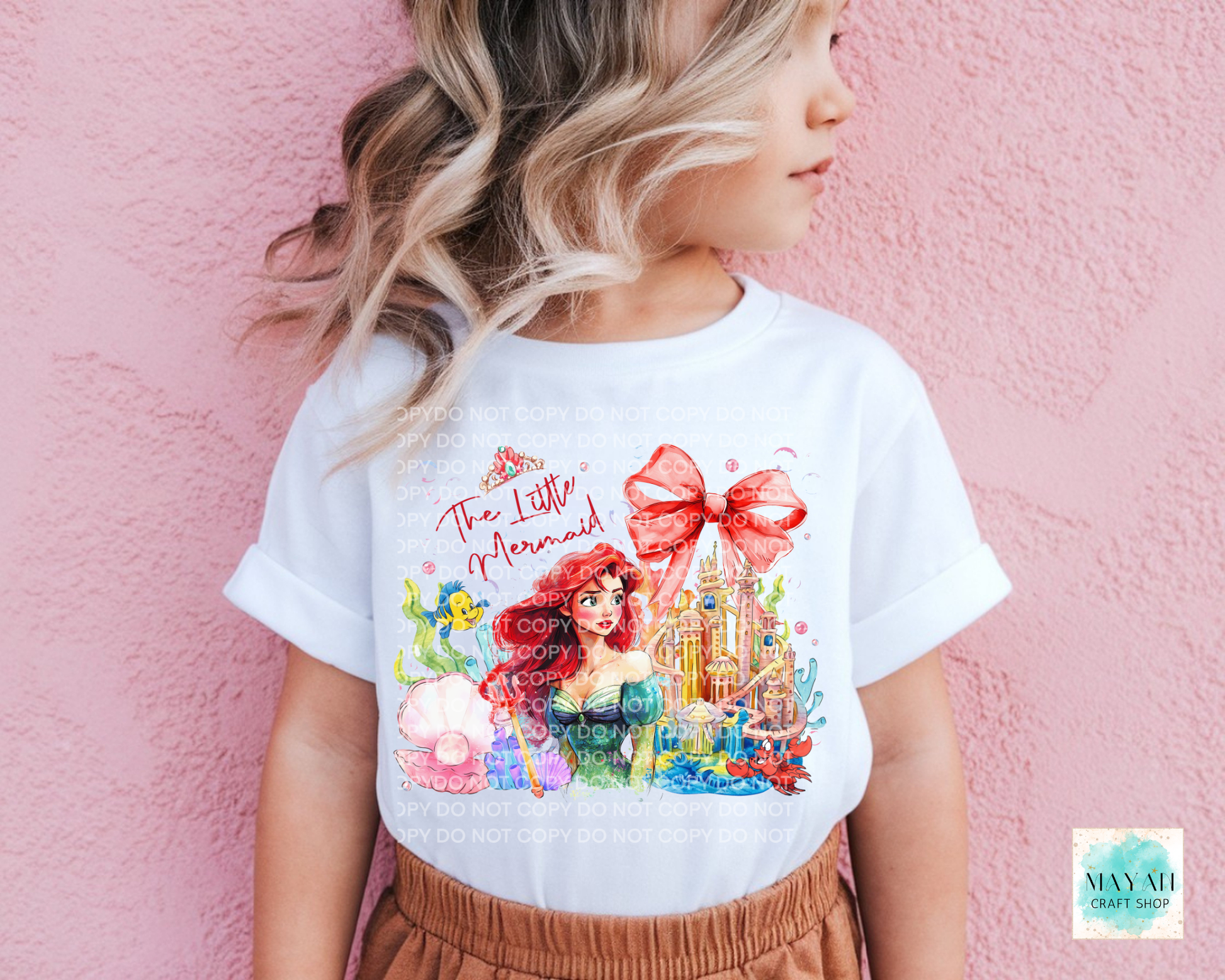 Child wearing a princess themed t-shirt against a pink background