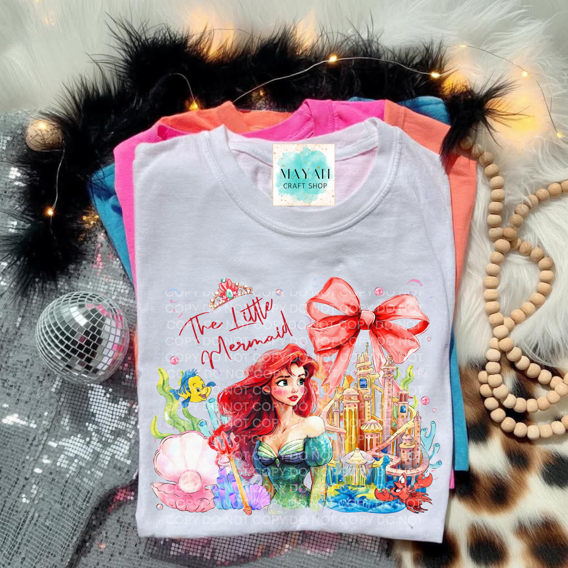 T-shirt with a mermaid design on a textured surface with decorative items.