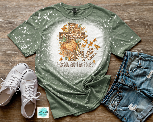 Green t-shirt with autumn design and text on a wooden surface with shoes and shorts.