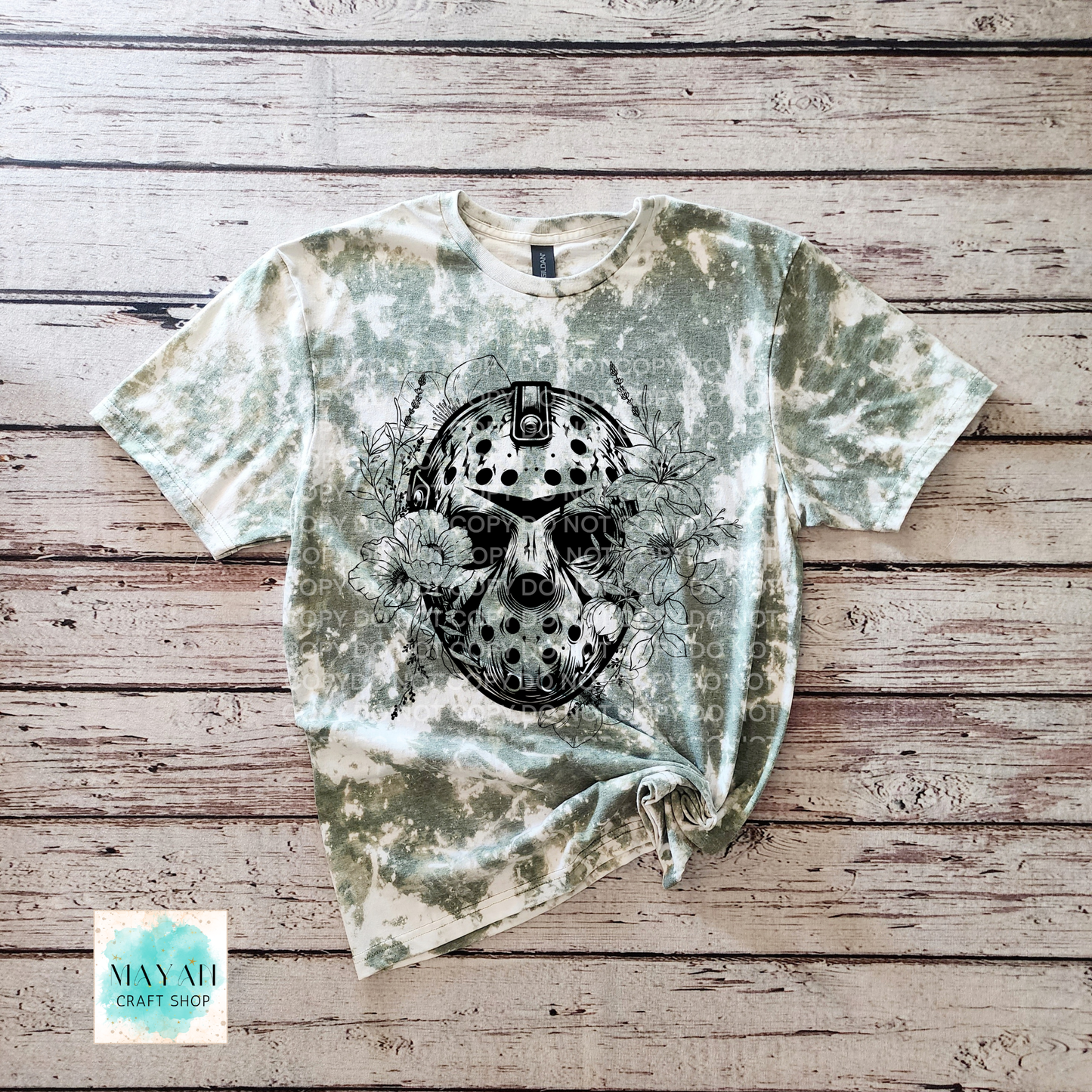 T-shirt with a graphic design on a wooden surface, featuring a brand logo in the corner.