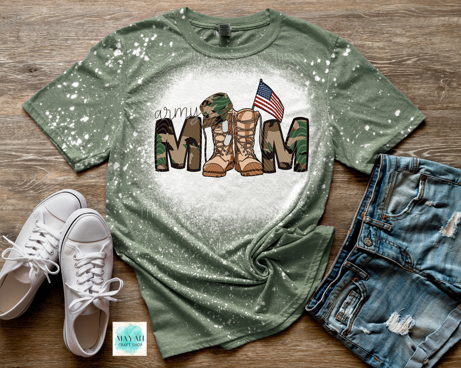Green t-shirt with military mom design on a wooden surface with shoes and shorts.