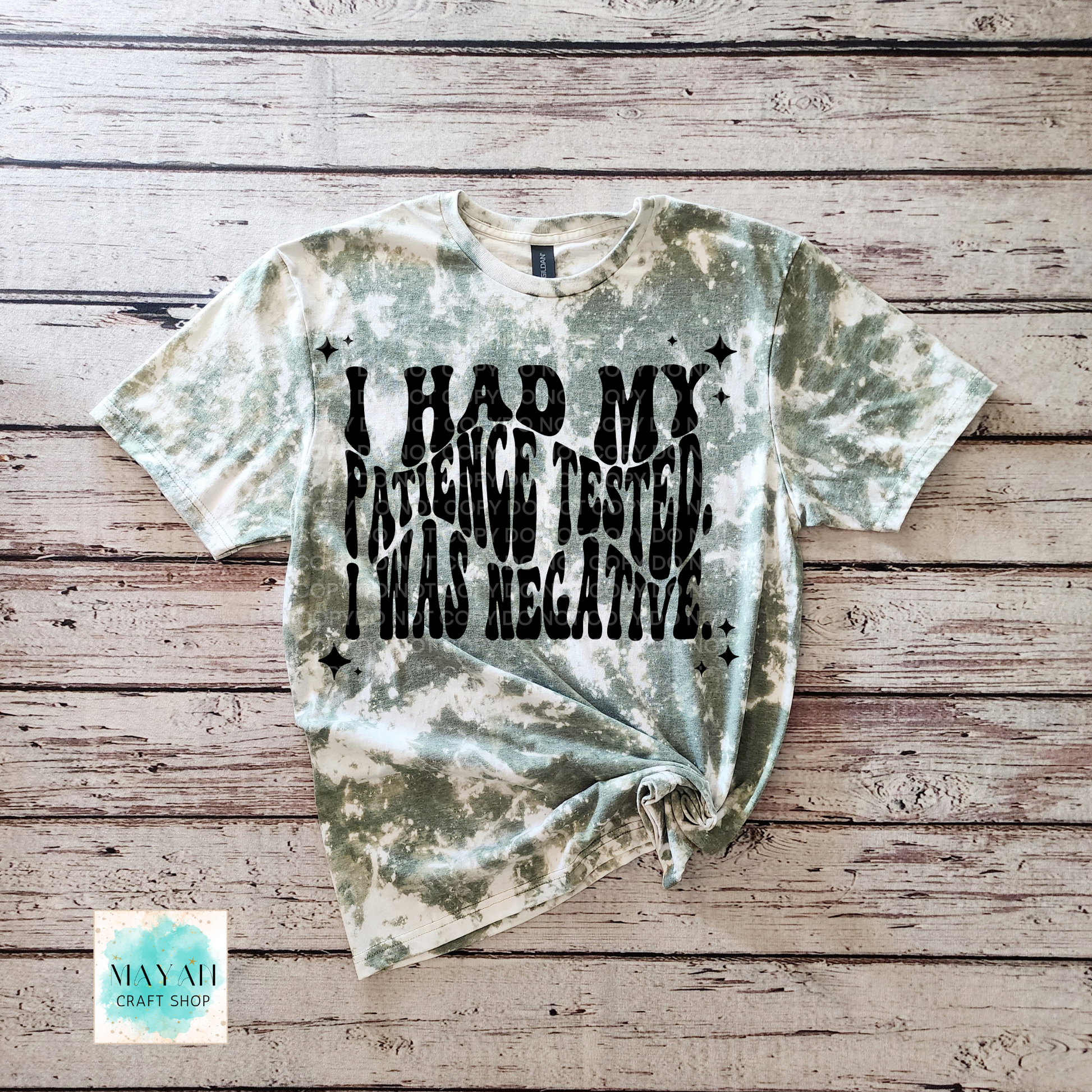 Dye-sublimated t-shirt with text on a wooden surface, featuring the brand 'Mayan Craft Shop'.