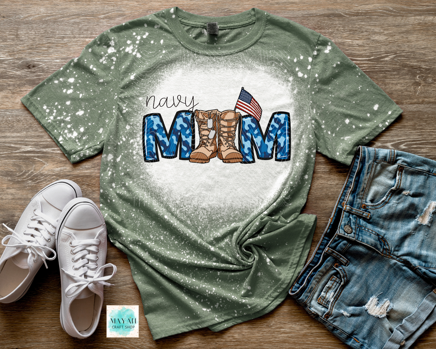Green t-shirt with military mom design on a wooden surface with shoes and shorts.