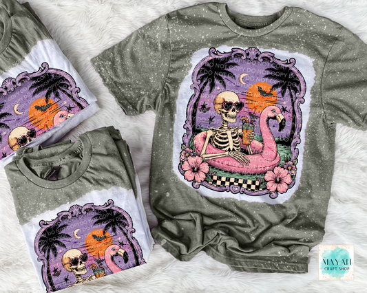 Military green t-shirts with a colorful skeleton and flamingo design on a white surface.