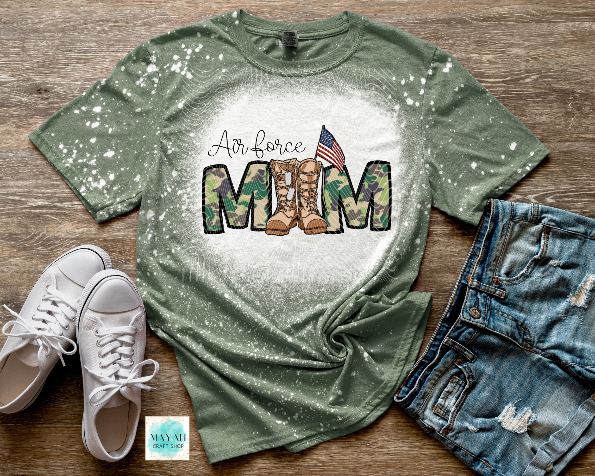 Green t-shirt with military mom design on a wooden surface with shoes and shorts.