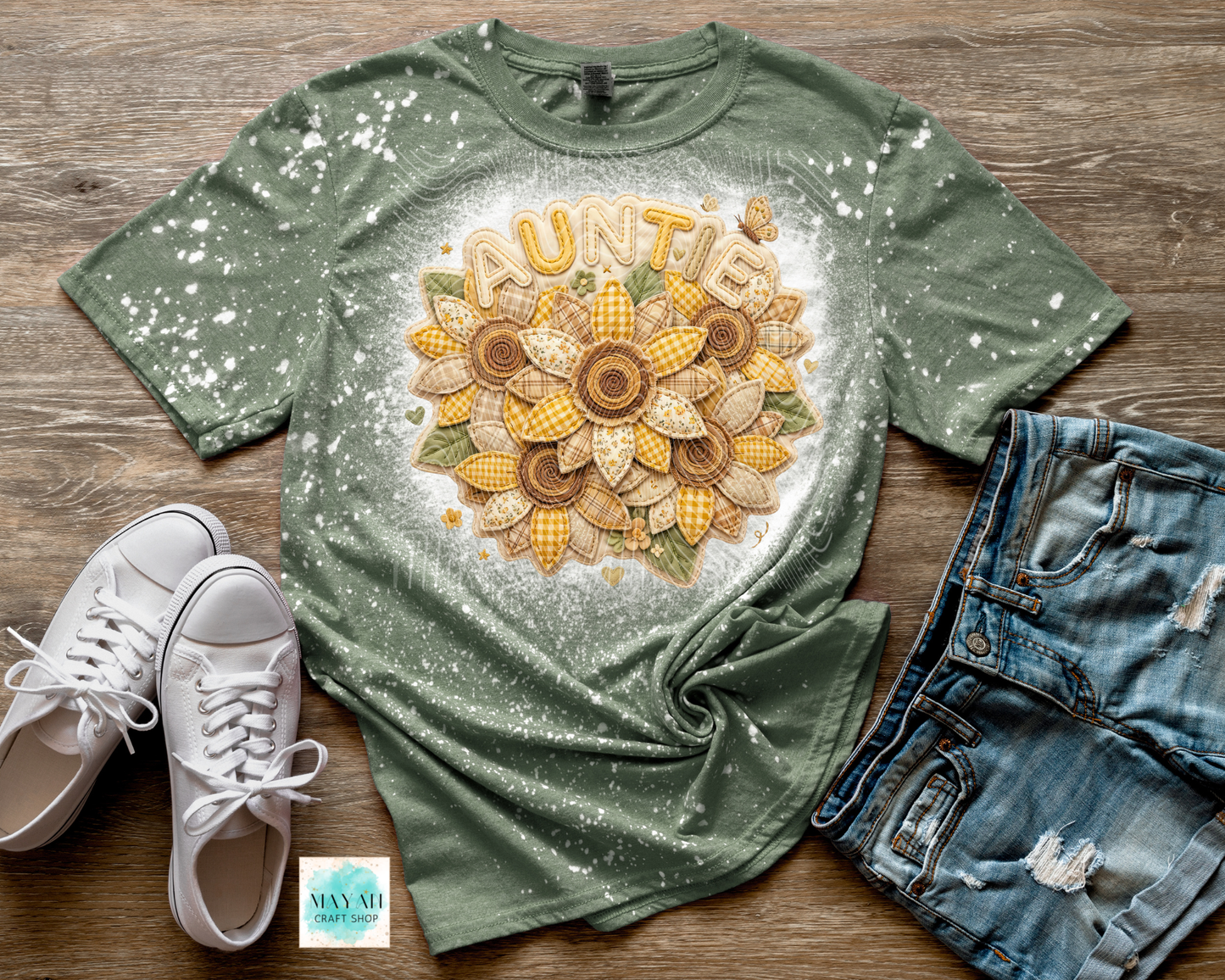 Green t-shirt with 'Auntie' design on a wooden surface with white sneakers and denim shorts.