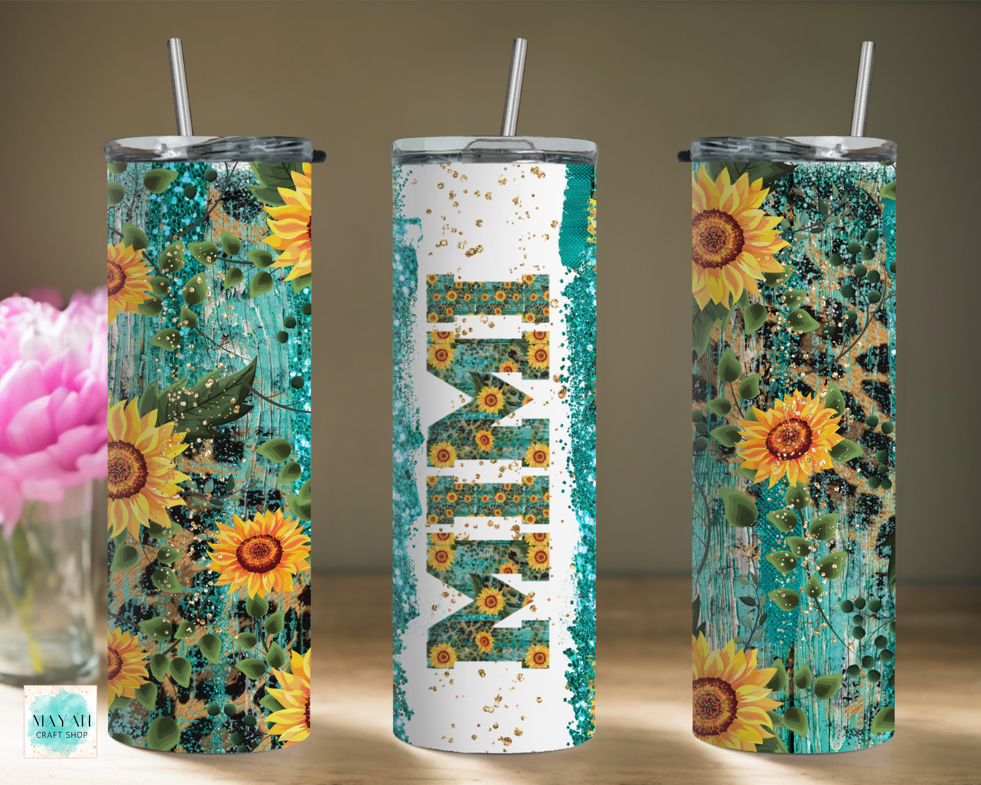 Three sunflower-themed tumblers with straws on a wooden surface.