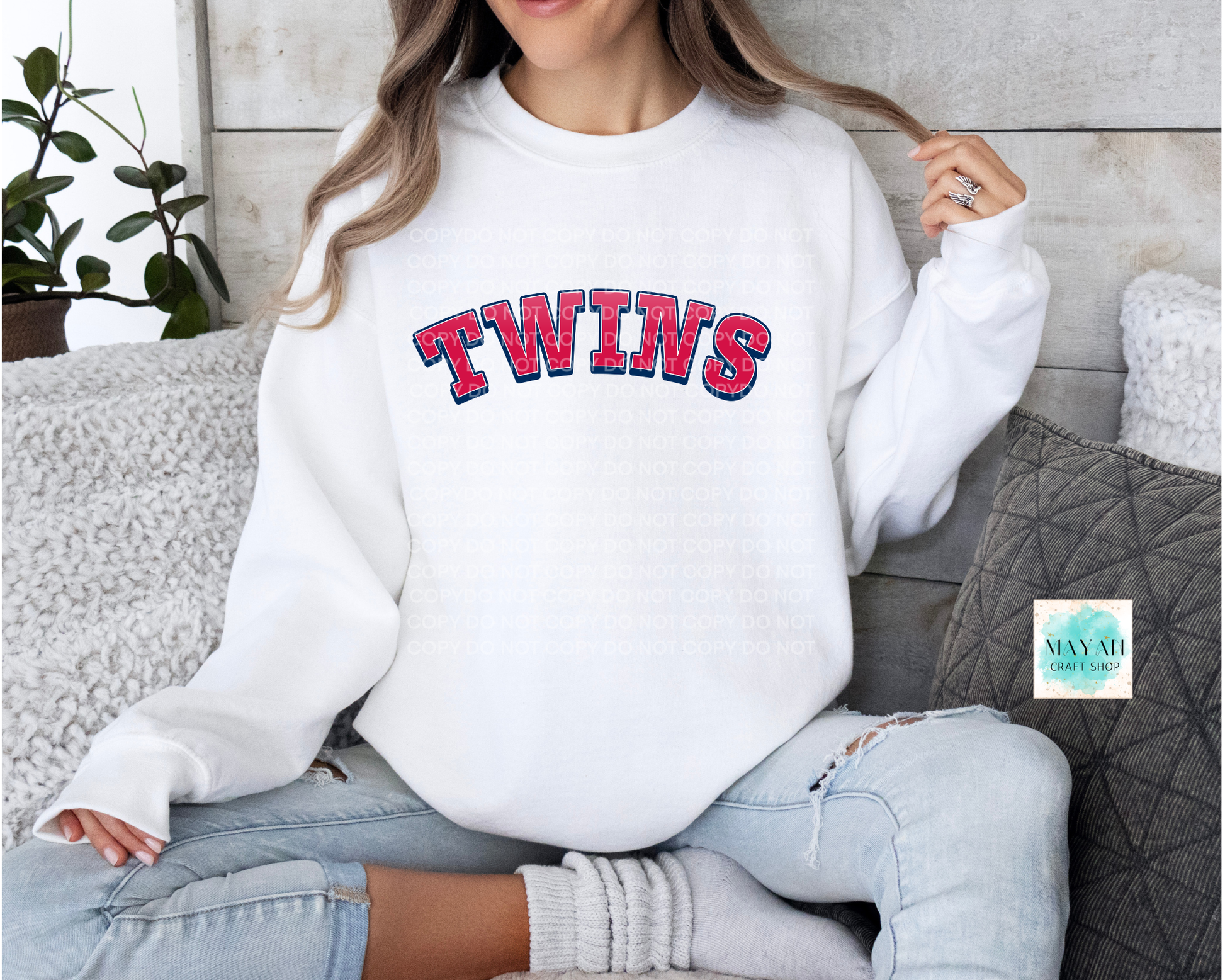 Person wearing a white sweatshirt with a baseball themed printed on it, sitting on a couch.