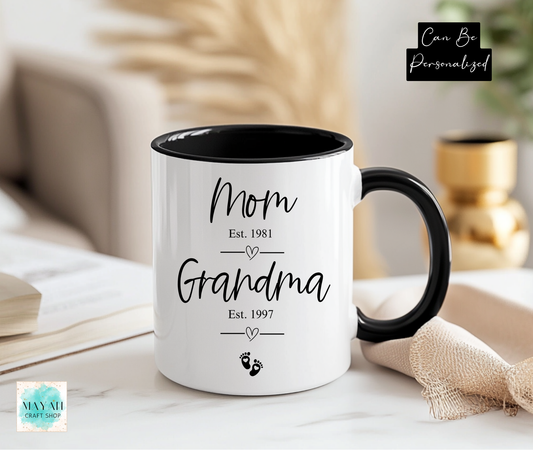White mug with black interior and handle displaying 'Mom Est. 1981' and 'Grandma Est. 1997' text.