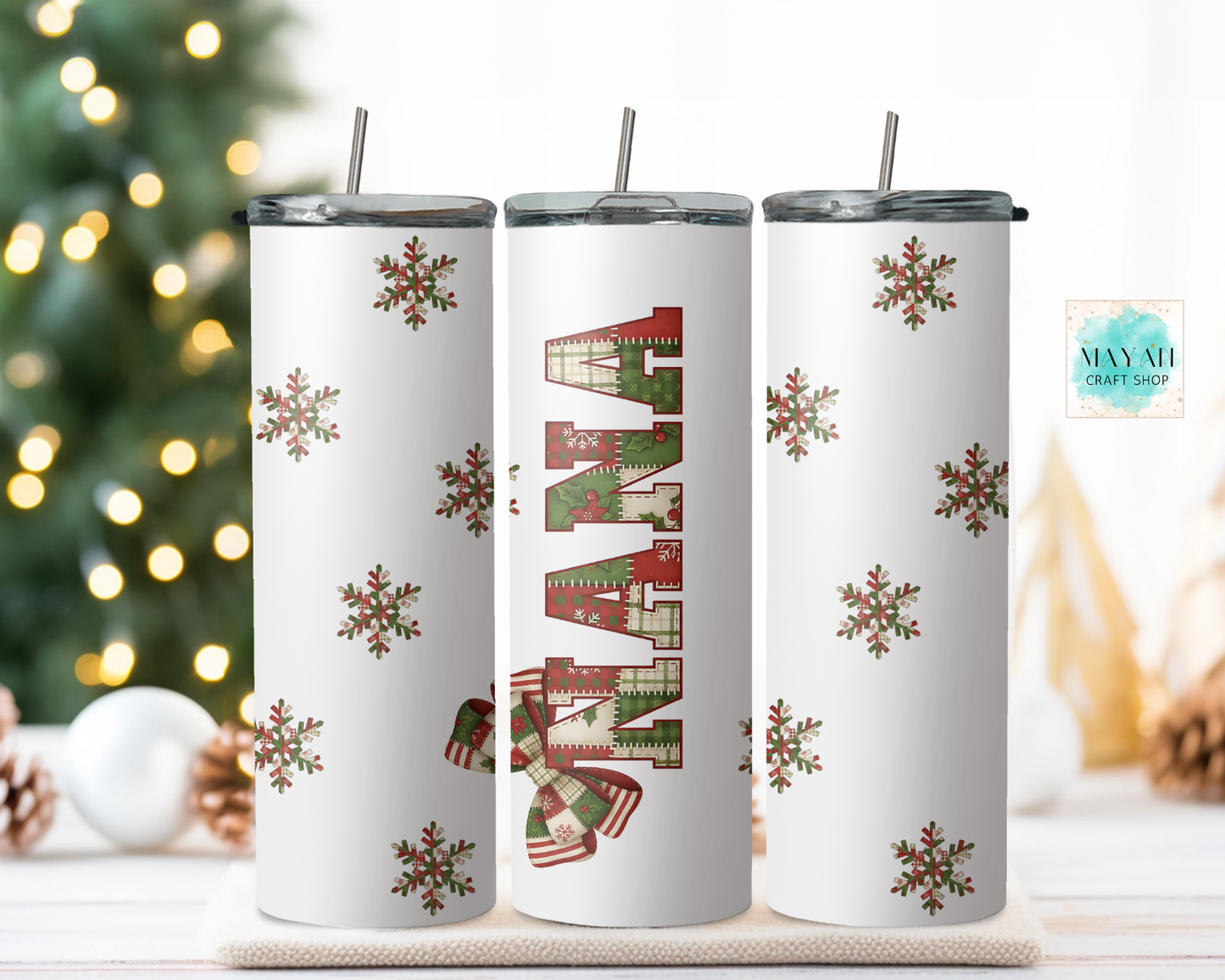 Three Christmas-themed tumblers with snowflakes and stockings on a white surface with a blurred festive background.