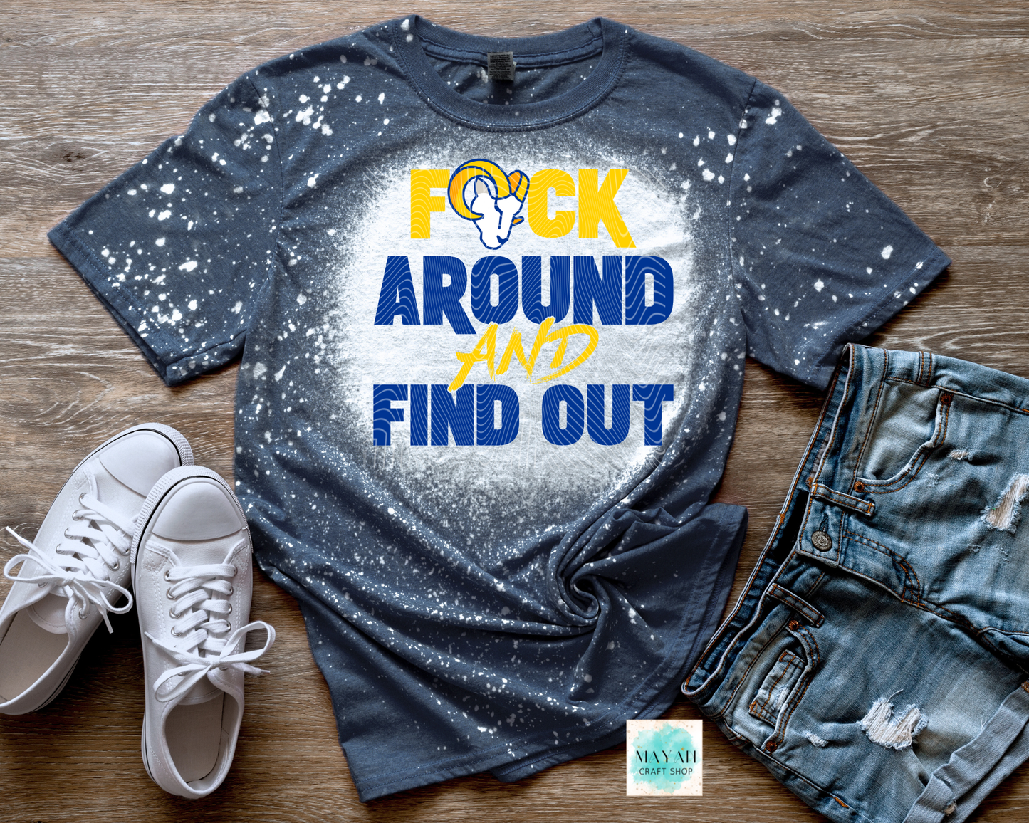 Bleached t-shirt with graphic design and text on a wooden surface with shoes and jeans.