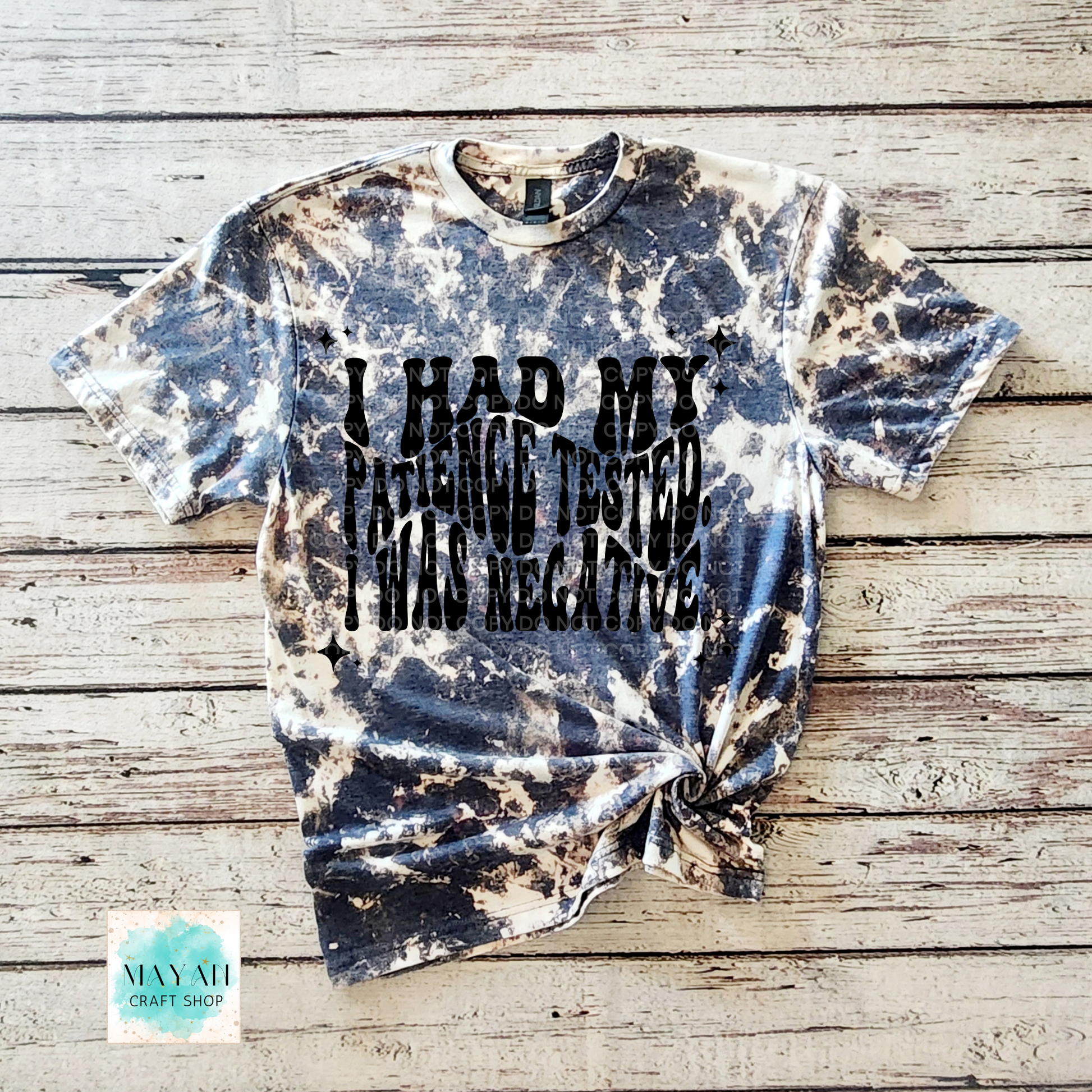 Tie-dye t-shirt with text on a wooden surface, featuring the brand 'Mayan Craft Shop'.