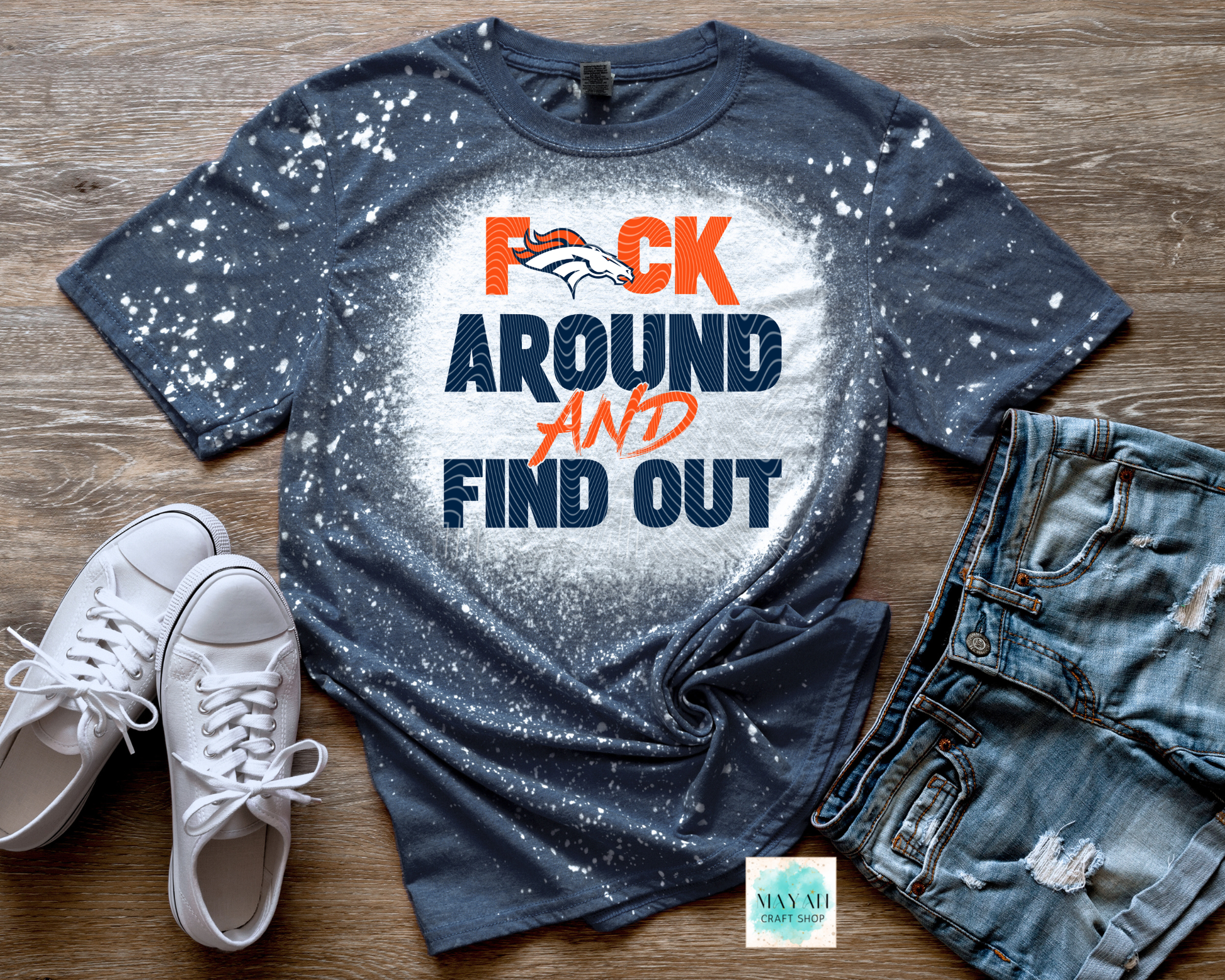 Bleached t-shirt with graphic design on a wooden surface with sneakers and jeans.