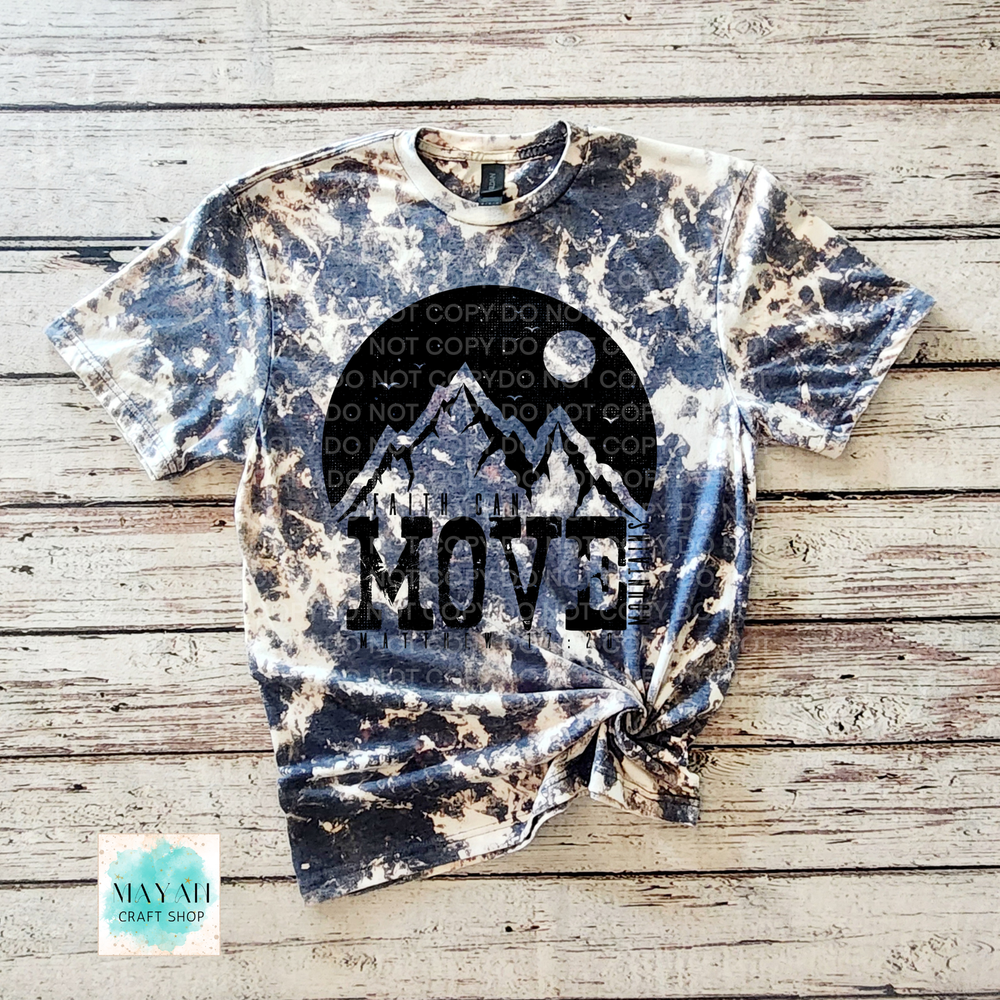 Bleached t-shirt with mountain design and 'MOVE' text on a wooden surface