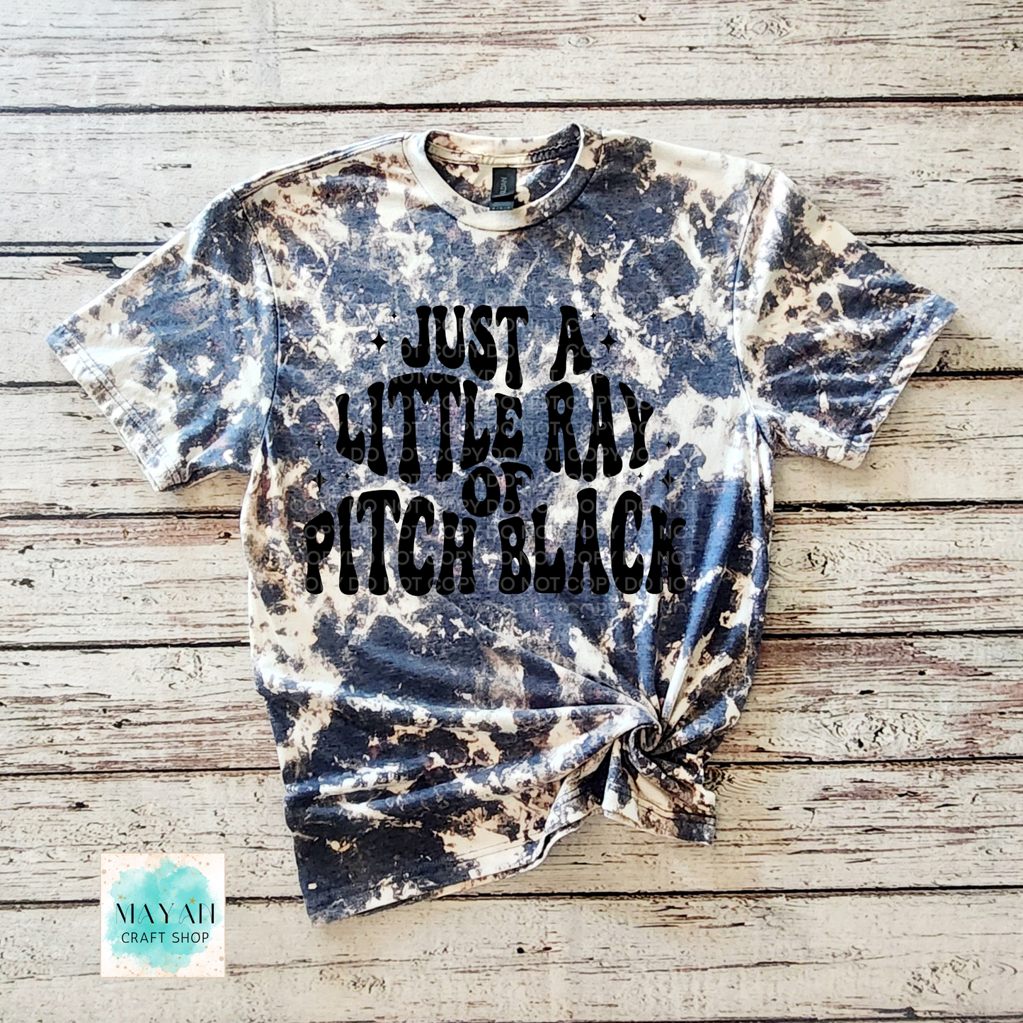 Tie-dye t-shirt with text on a wooden surface, featuring the brand 'Mayan Craft Shop'.