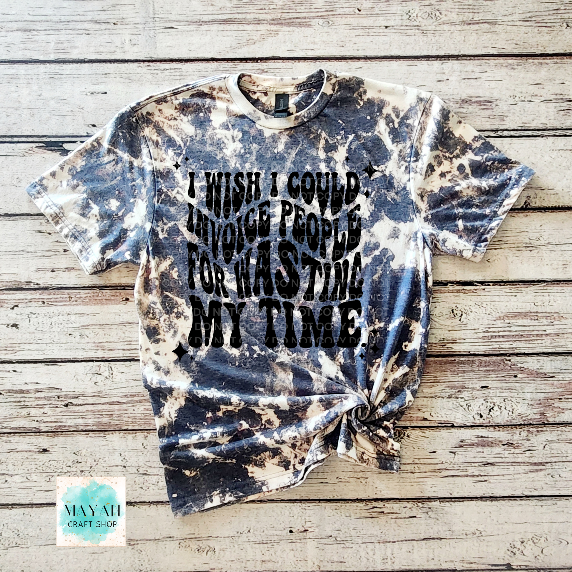 Tie-dye t-shirt with text on a wooden surface, branded 'Mayan Craft Shop'.