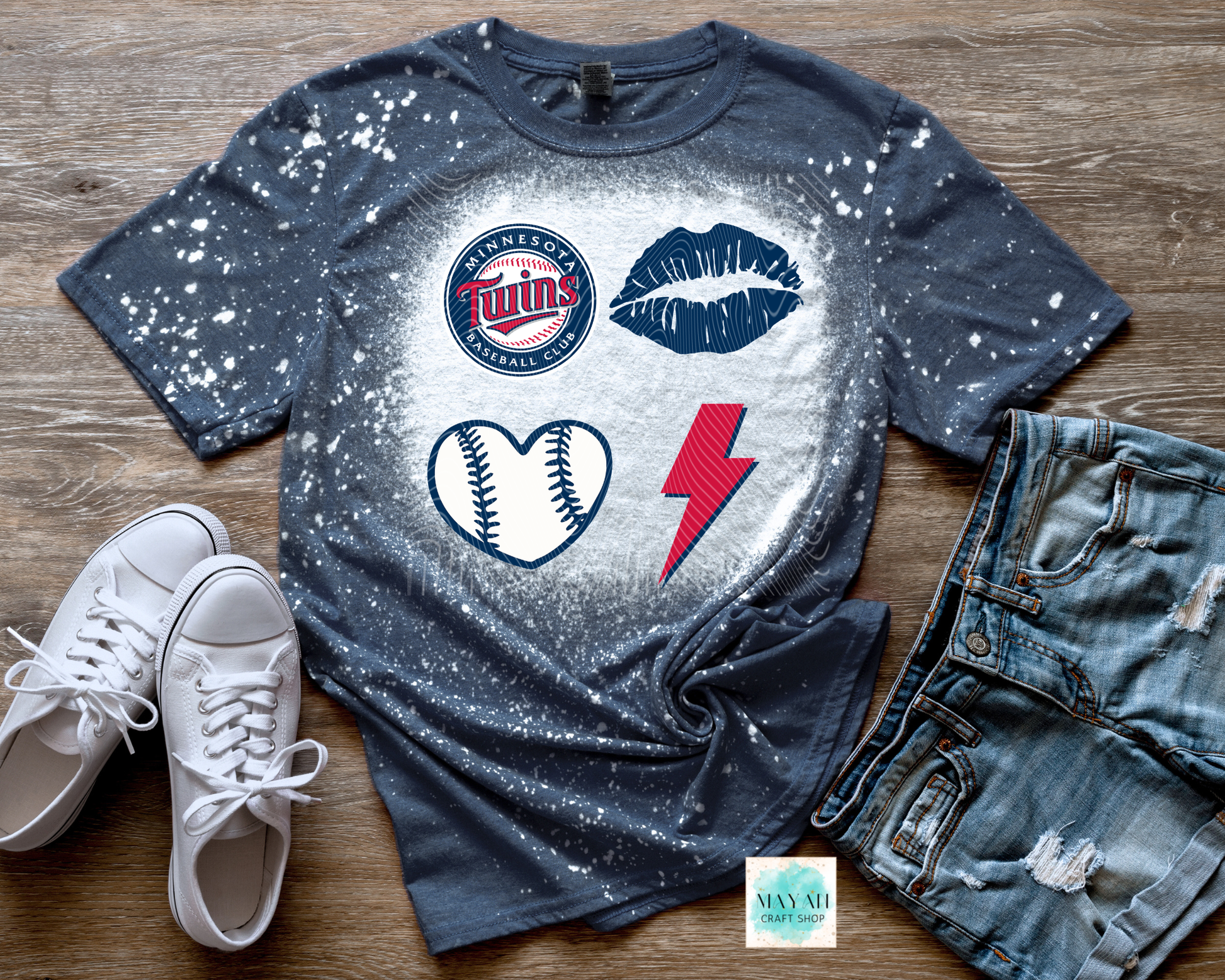 Gray t-shirt with sports-themed graphics on a wooden surface with white sneakers and jeans.