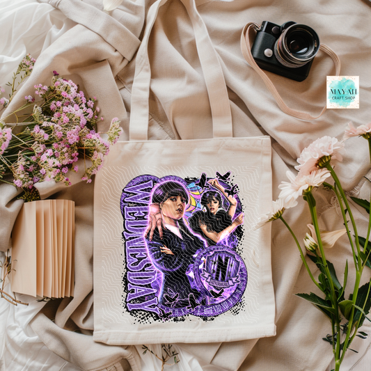 Tote bag with artistic design on a soft fabric background with flowers and a camera.
