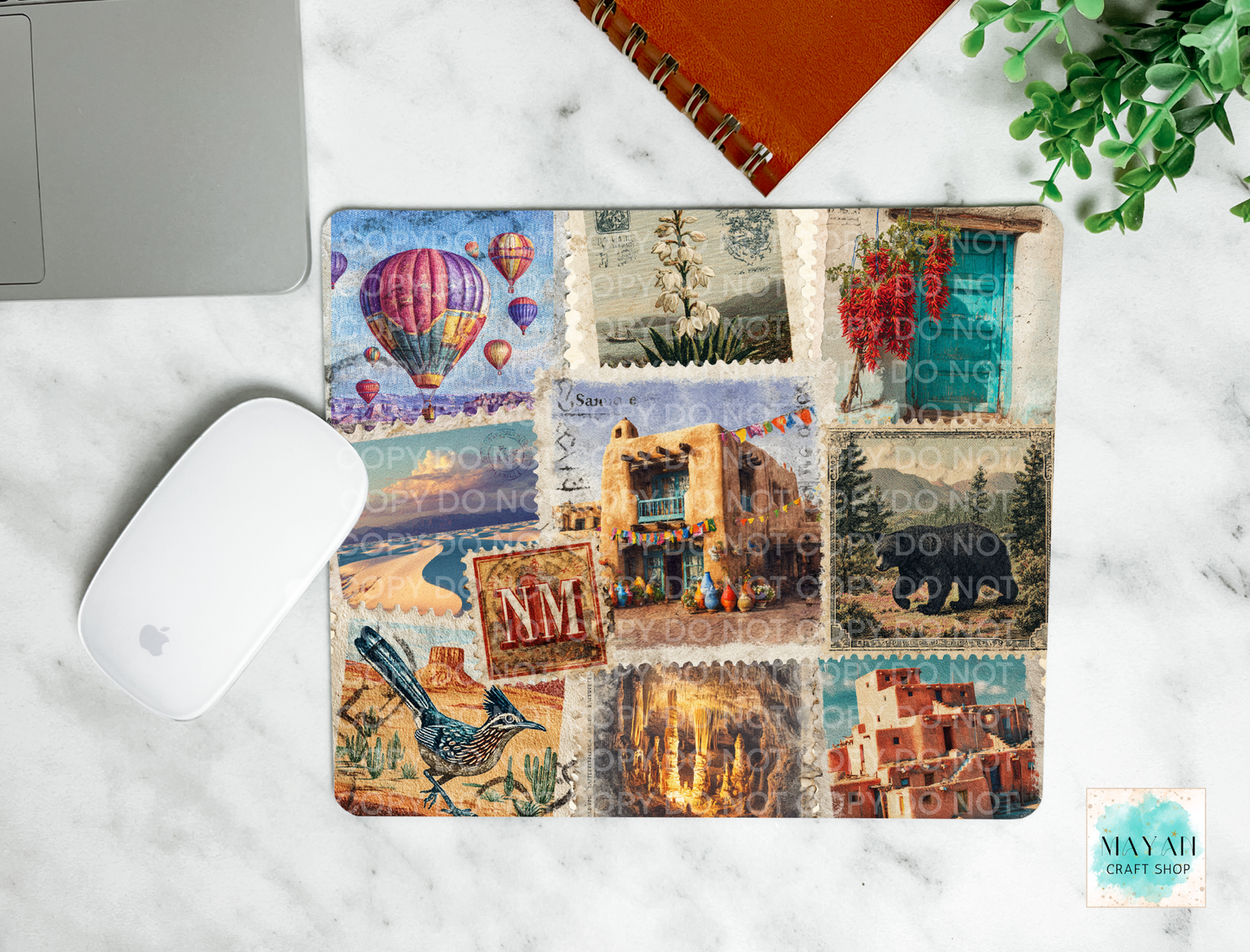 Laptop with a decorative mouse pad featuring travel-themed images on a marble surface.