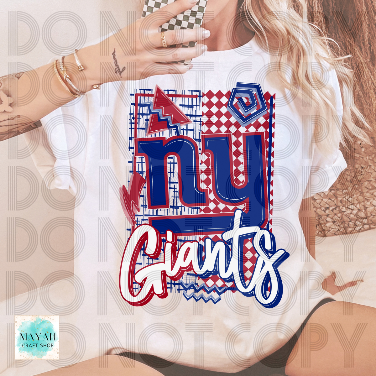 A woman wearing a white graphic T-shirt with a large red, white, and blue design on the front. The shirt features a patterned background with red and white diamonds, blue lettering, and white script.