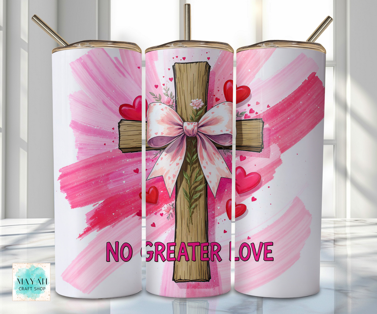 Three tumblers with a cross, bow, and hearts design on a pink background.