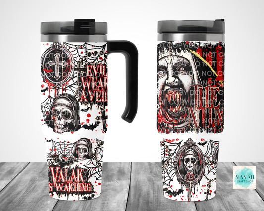 Two views of a travel tumbler mug with a gothic horror design featuring skulls, spiders. The tumbler has a black handle and lid, shown on a gray wood-textured background.
