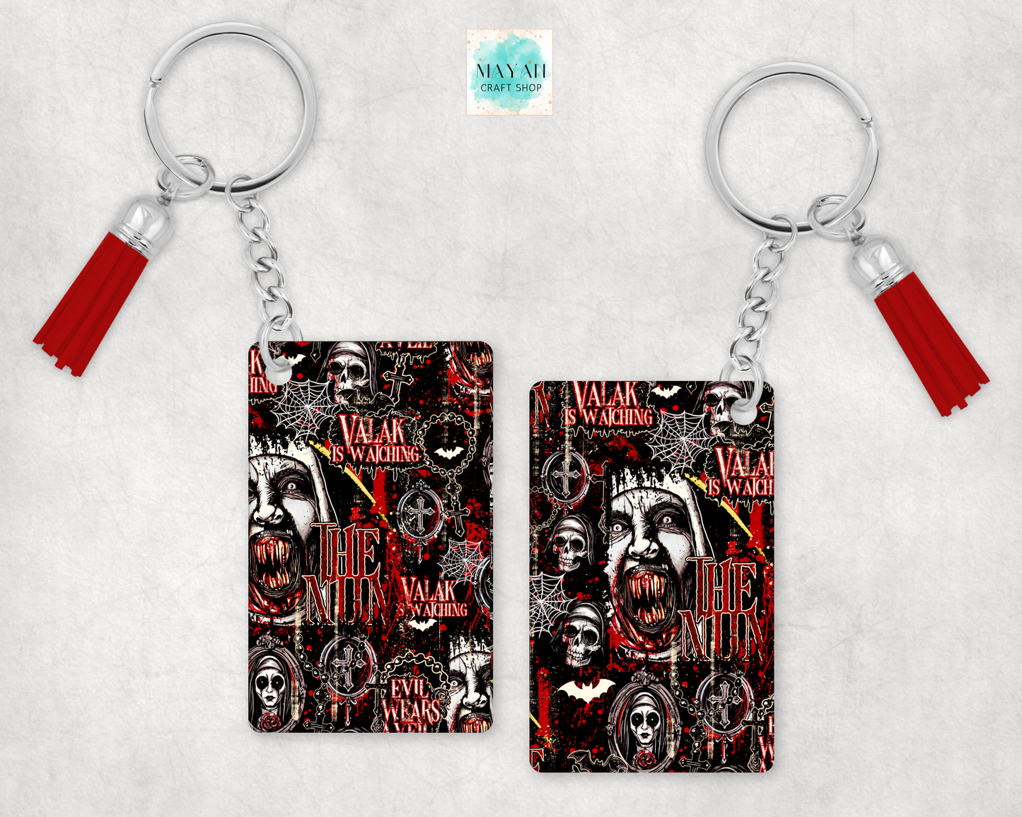 Two keychains with red tassels, featuring a gothic theme with skulls, teeth, and words on a light gray textured background.