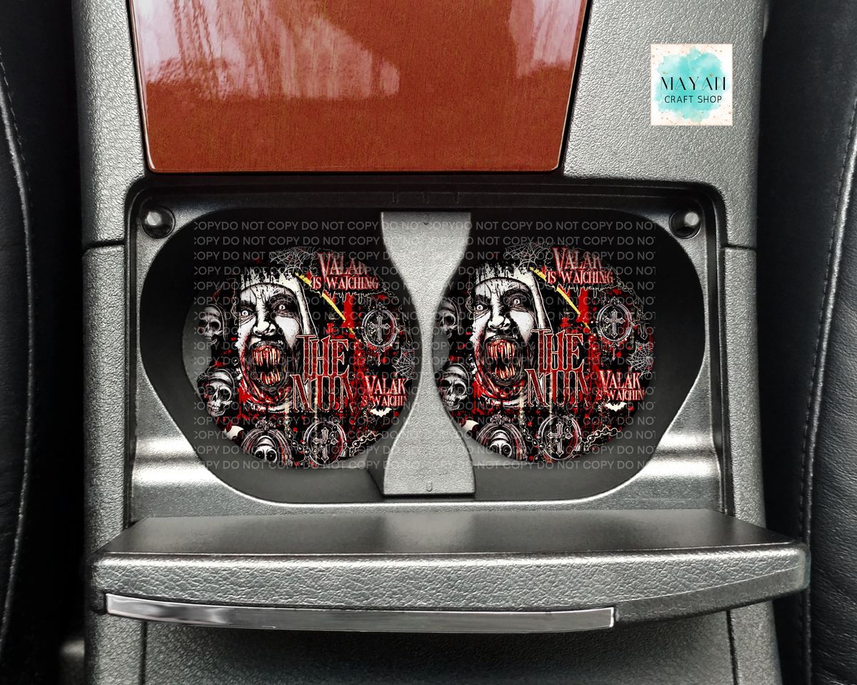 A pair of car cup holders installed in a center console, featuring a detailed graphic print of a woman's face with a bandana and red text, set against a dark gray car interior.