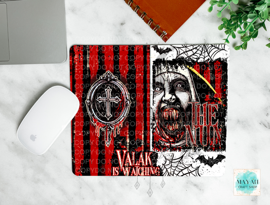 Amouse pad with a gothic Halloween design featuring a vampire woman's face, bats, spiders, and red-and-black striped background. The mat is shown in a flat-lay on a white marble surface with a white mouse, part of a laptop, an orange notebook, and green leaves.
