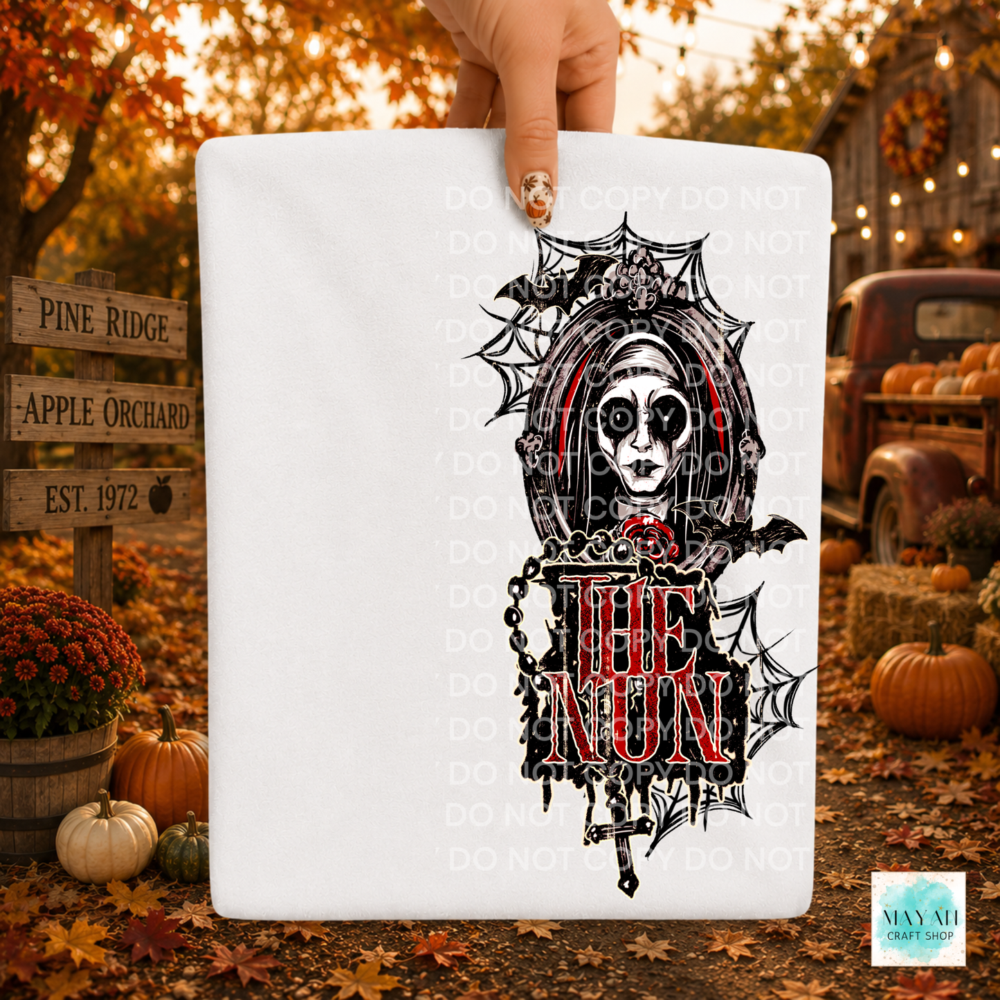 A hand holds a white shirt or board featuring a gothic-style black spiderweb and skull illustration with the in red and black. The scene is set outdoors in autumn with pumpkins, fall leaves, a rustic truck, and a fence, with repeated 'DO NOT COPY' watermarks across the image.